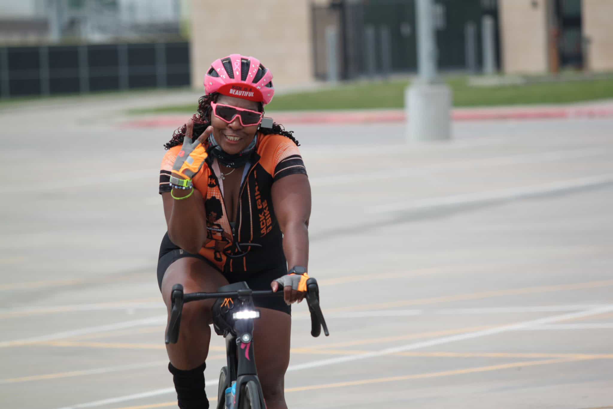 Bright female cyclist wearing pink helmet and sunglasses smiling during Bluebonnet Express ride.