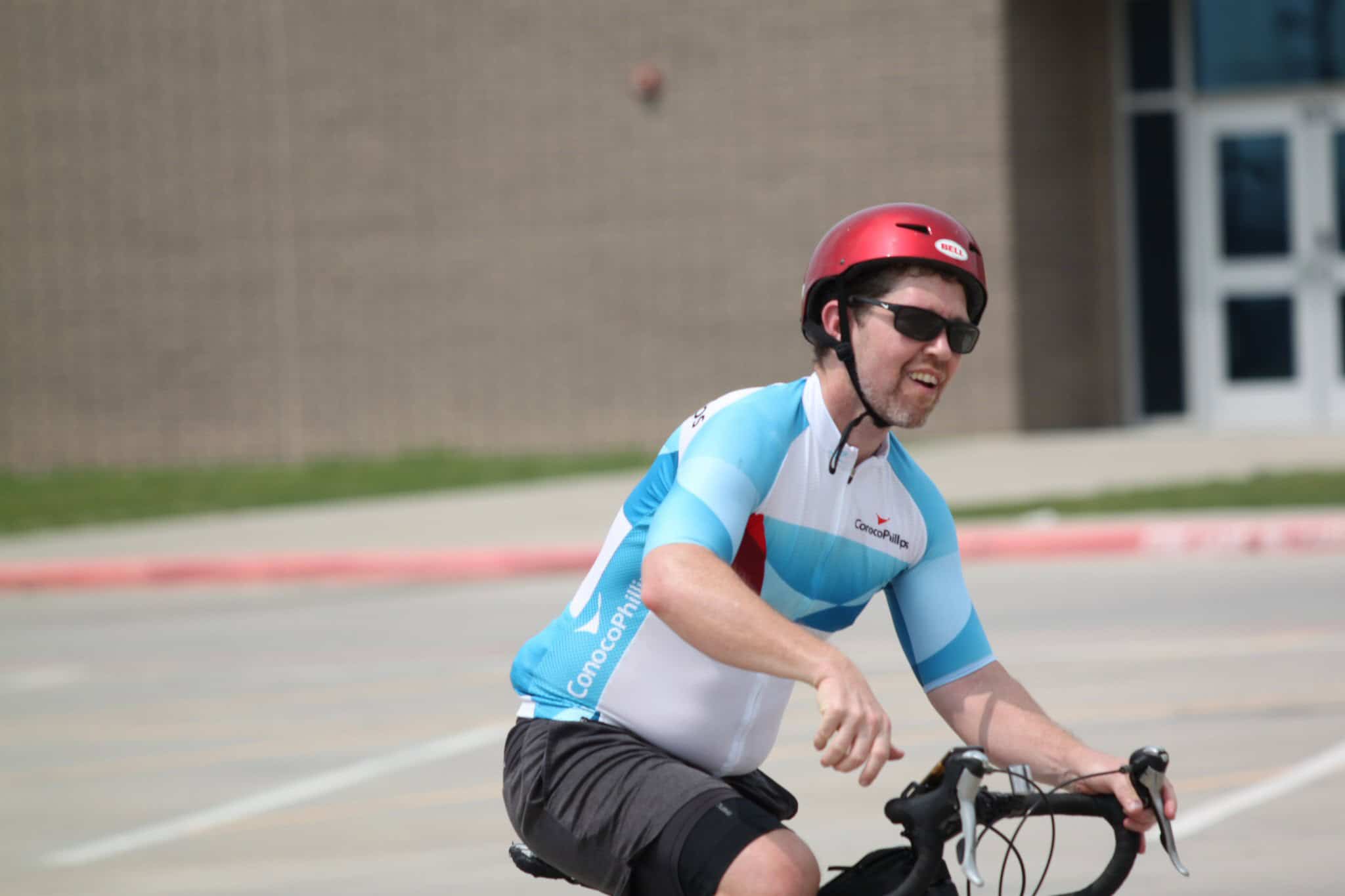 Bright cyclist in blue and white jersey with red helmet riding bike, promoting Bluebonnet Express.
