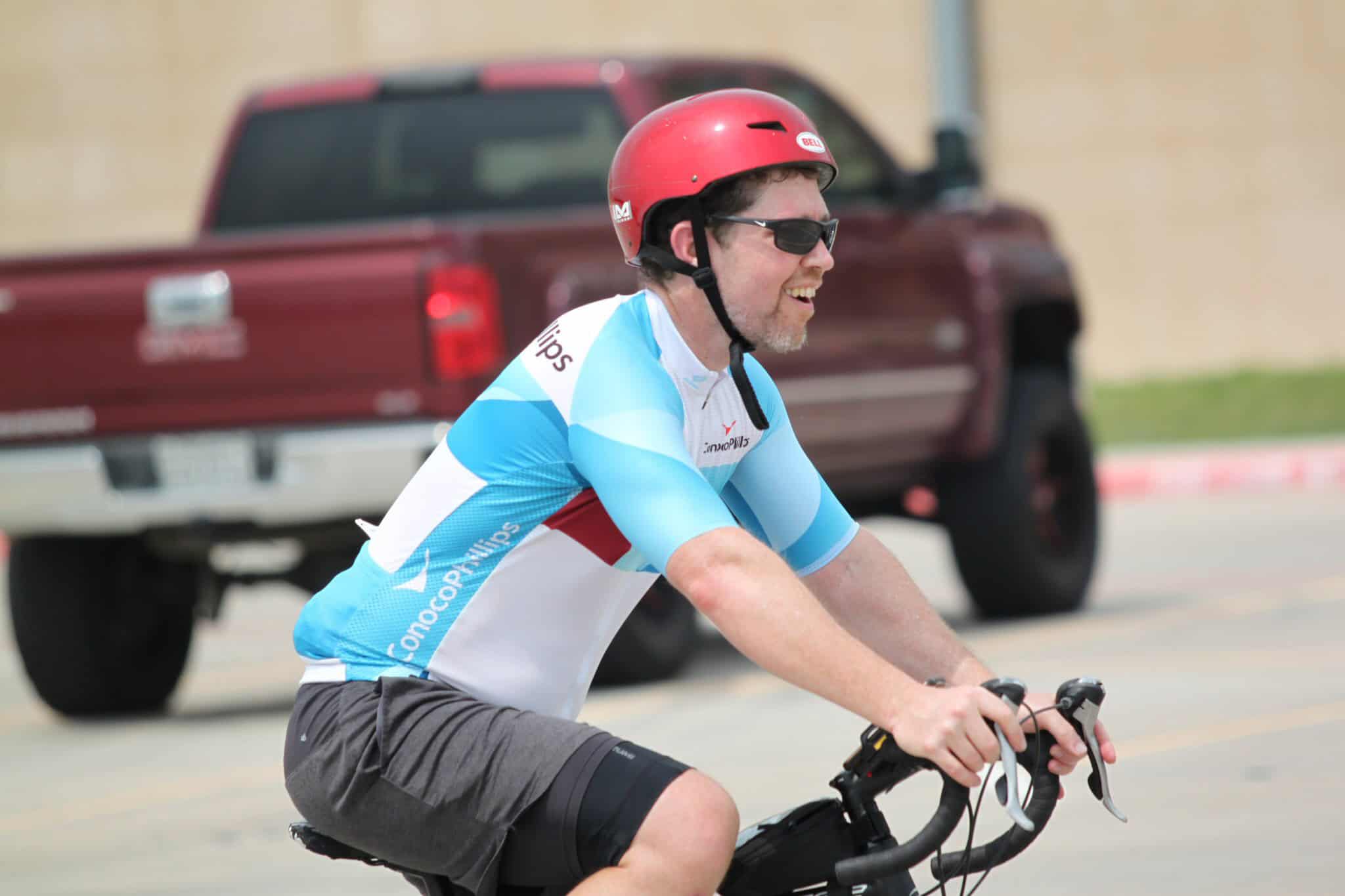 Bike rider in Bluebonnet Express cycling jersey, wearing helmet and sunglasses.