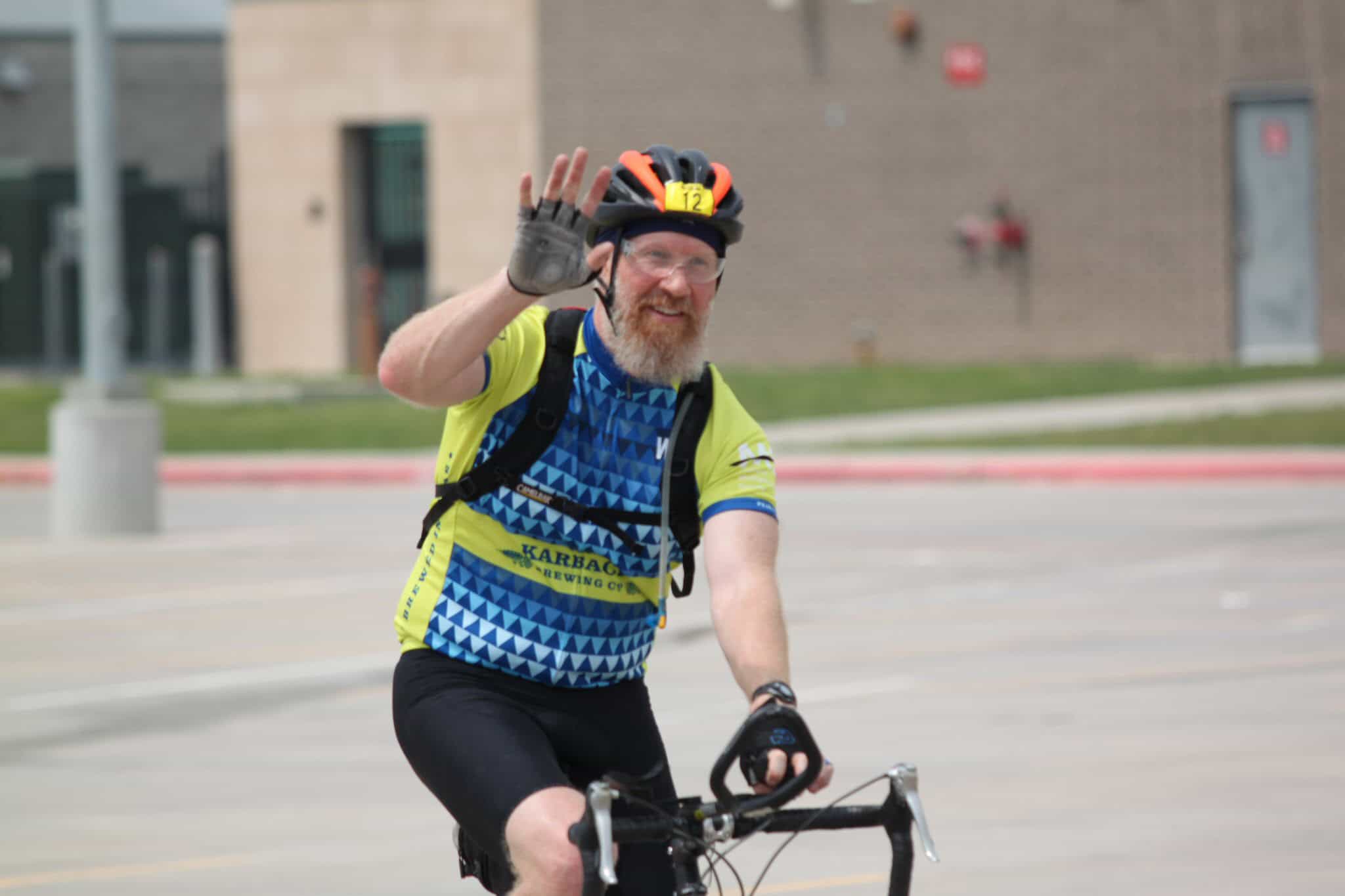 Bright cyclist waving during Bluebonnet Express bike race event in Texas.