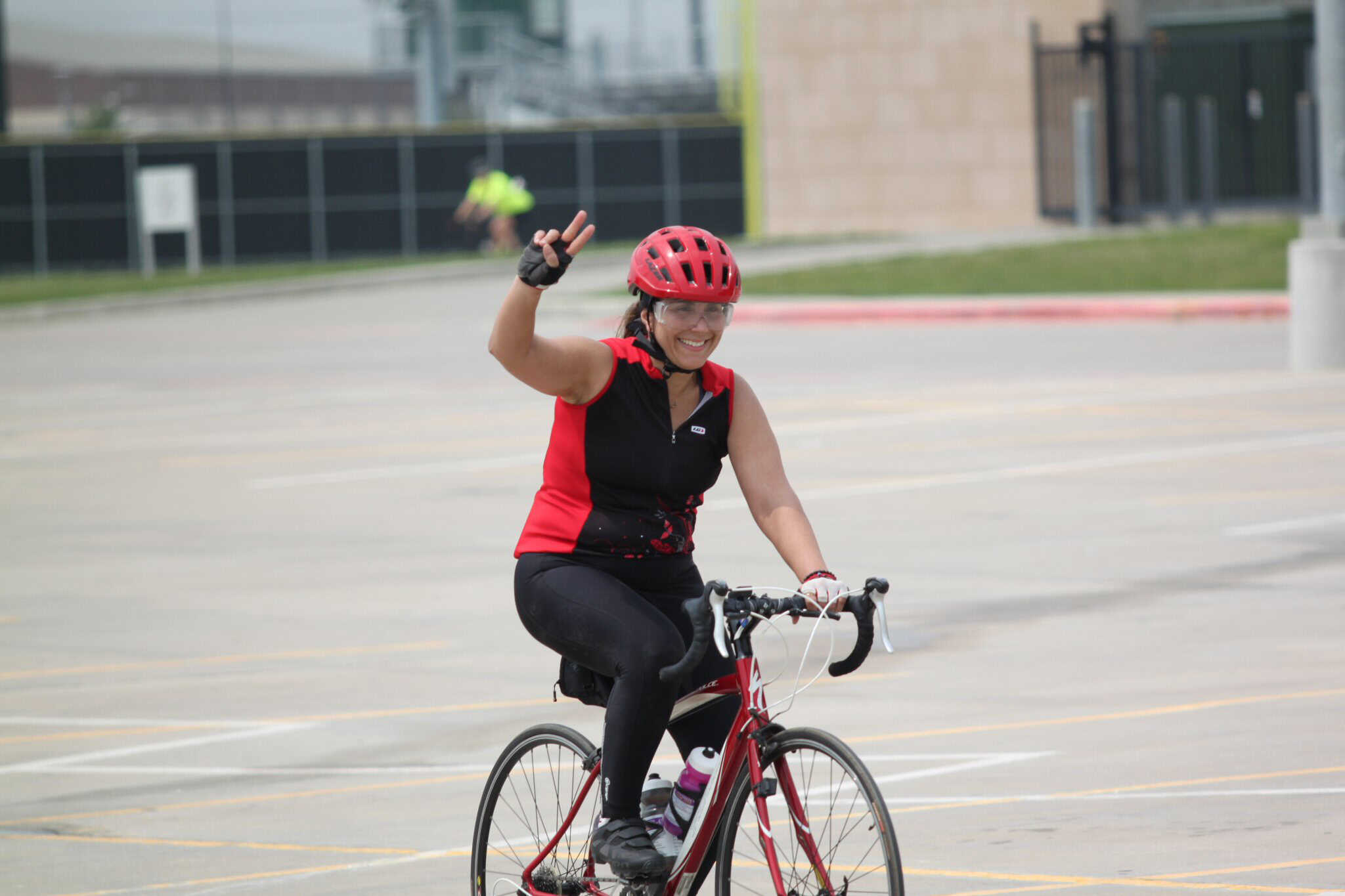 Vibrant cyclist in helmet smiling and waving during Bluebonnet Express event outdoors.