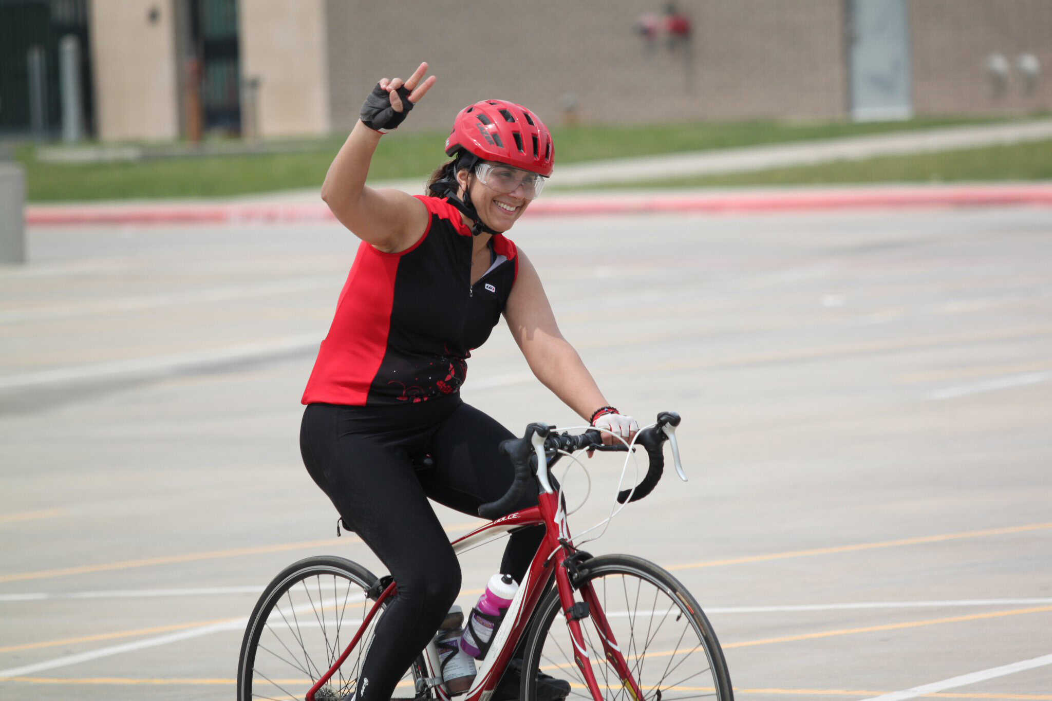 Bright red helmet and sporty cycling gear on female cyclist riding on an outdoor track.