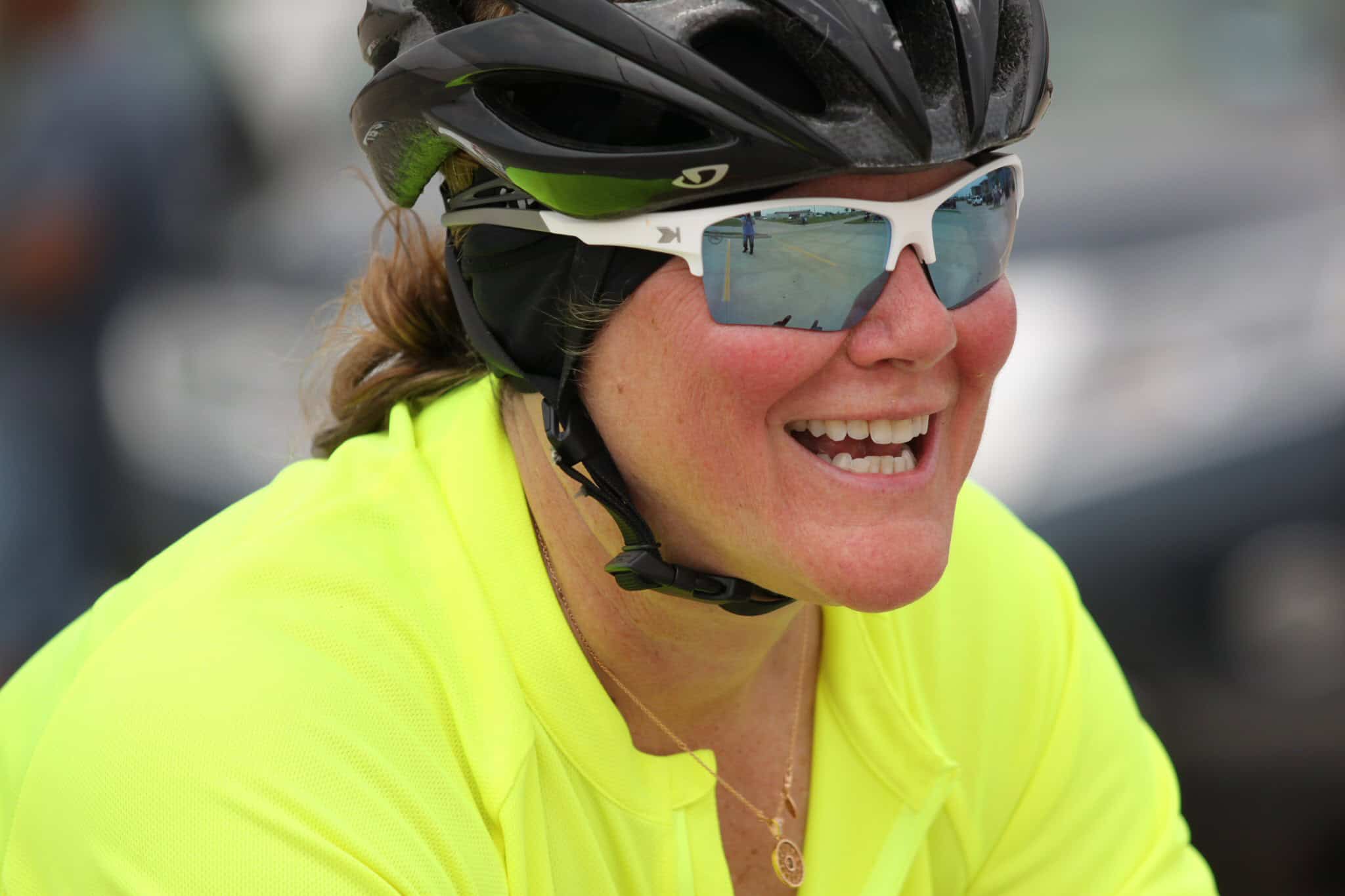 Smiling cyclist wearing sunglasses and helmet, enjoying Bluebonnet Express bike ride outdoor.