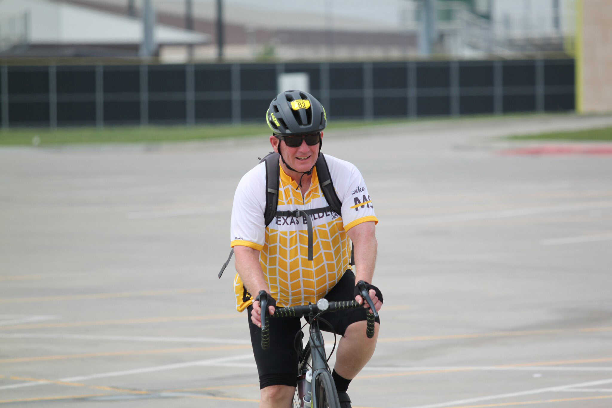 Man riding bicycle at Bluebonnet Express event, wearing helmet and cycling gear in an outdoor parking lot.