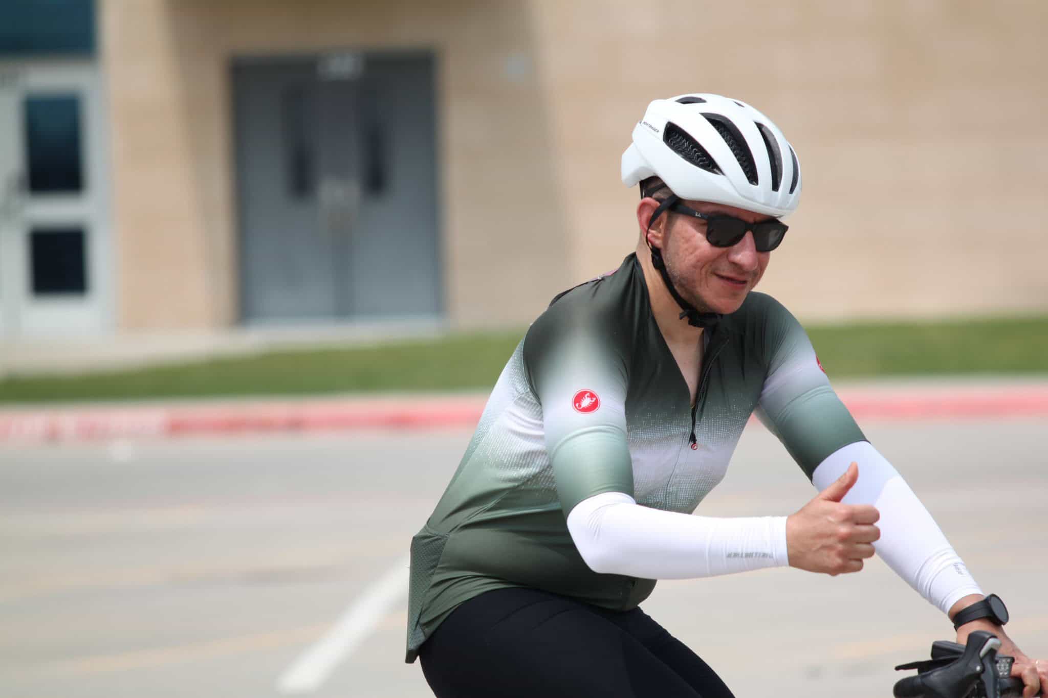 Fast cyclist wearing helmet and sunglasses, promoting eco-friendly transportation on Bluebonnet Express route.