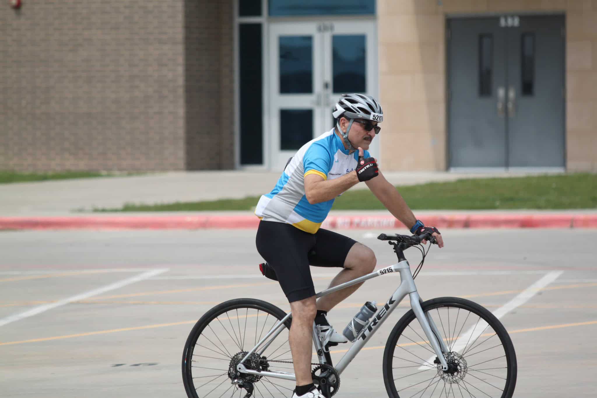 Man riding Trek mountain bike during outdoor cycling event, wearing helmet and athletic gear.