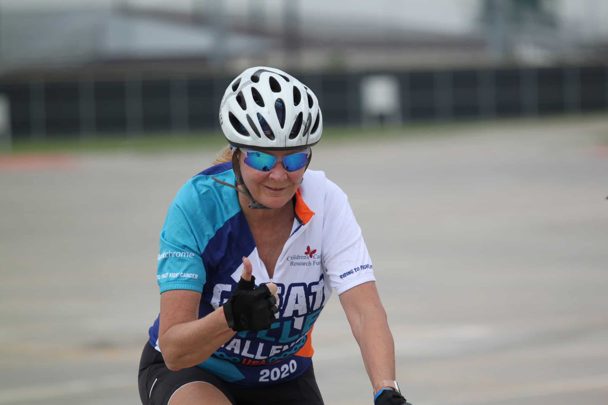 High-energy woman cyclist wearing helmet and sunglasses during Bluebonnet Express bike event.