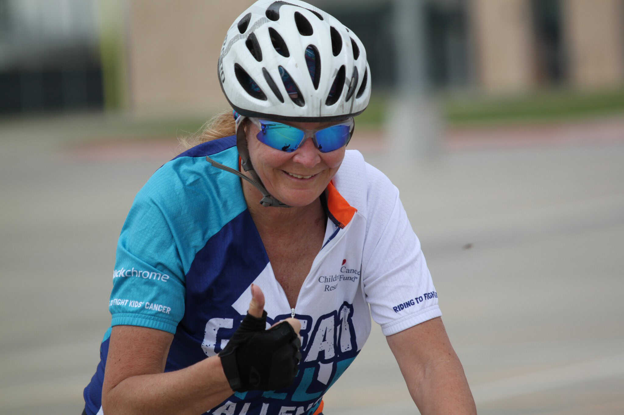 Woman cycling in Bluebonnet Express event, wearing helmet and sunglasses for safety and comfort.