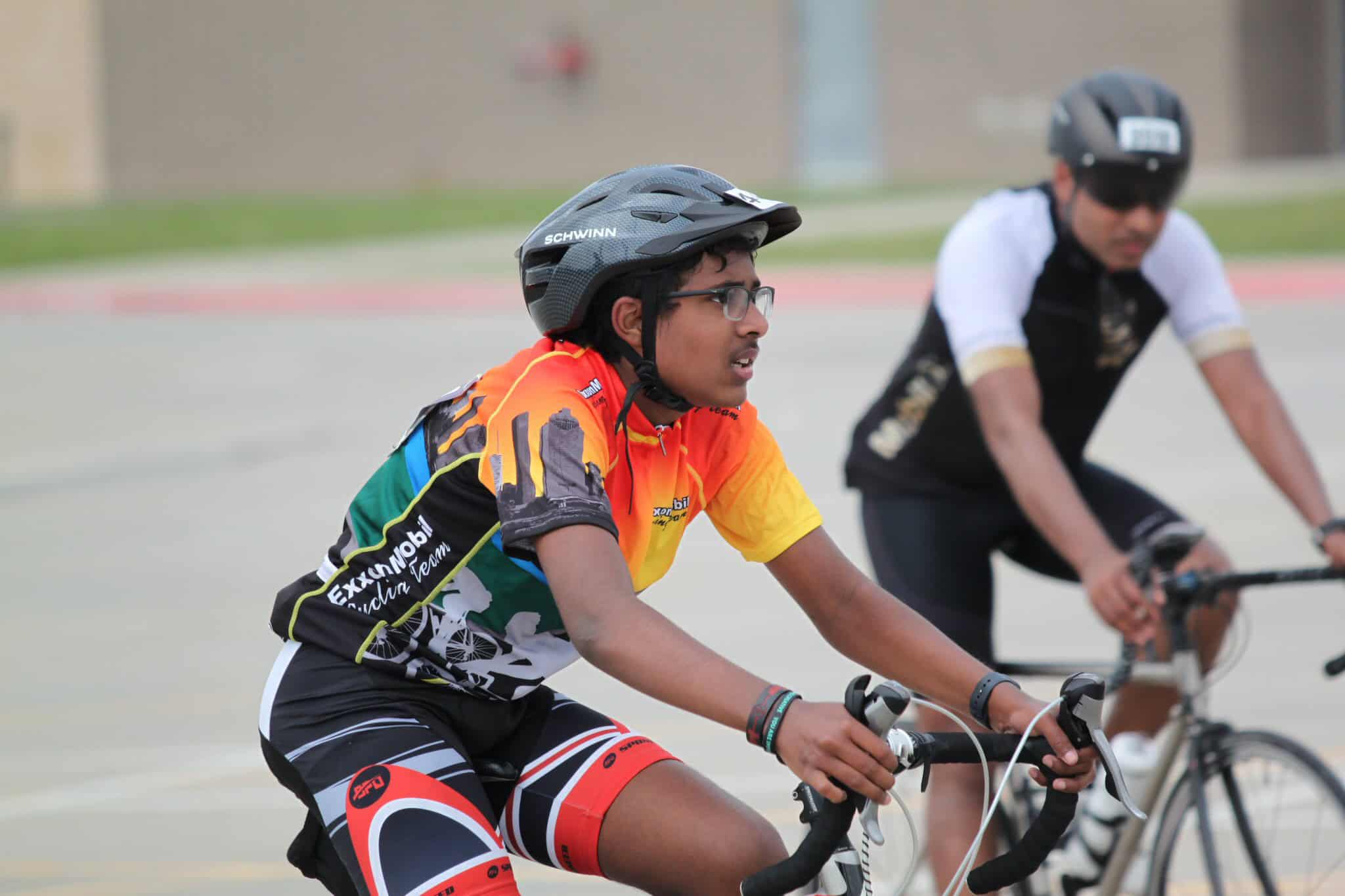 Youth cyclist participating in a bike race, wearing a helmet and colorful team jersey.