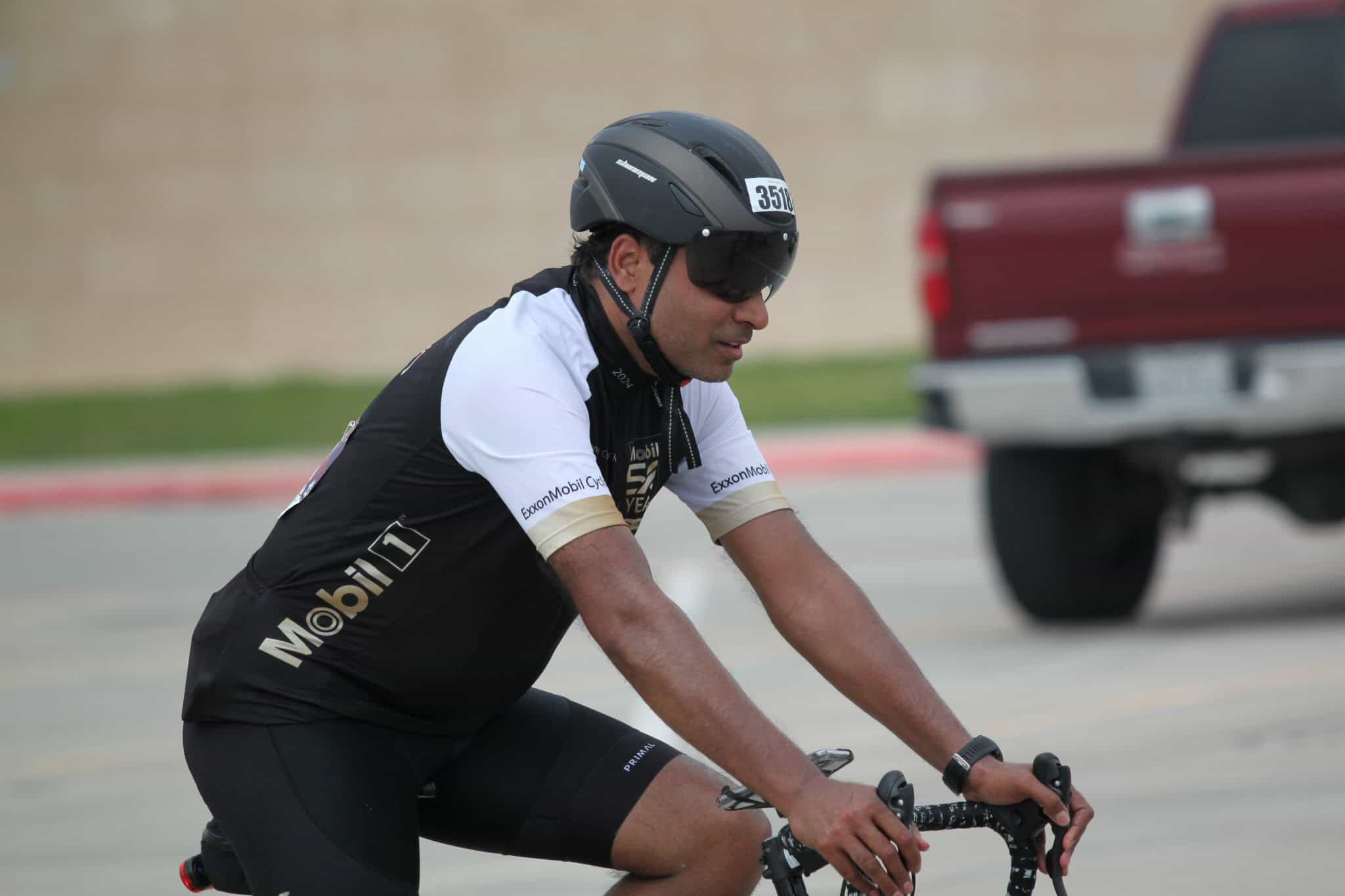 High-performance cyclist wearing a helmet and sunglasses during a race, promoting eco-friendly transportation.
