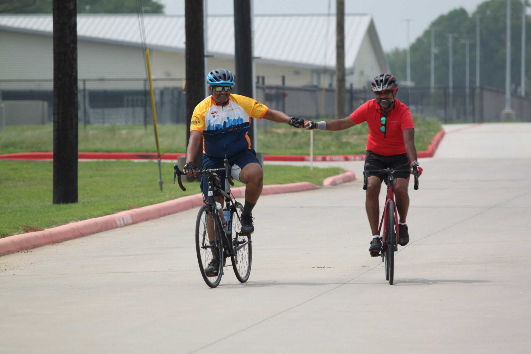 Happy cyclists riding on a paved trail, celebrating with a high-five in a scenic outdoor setting.