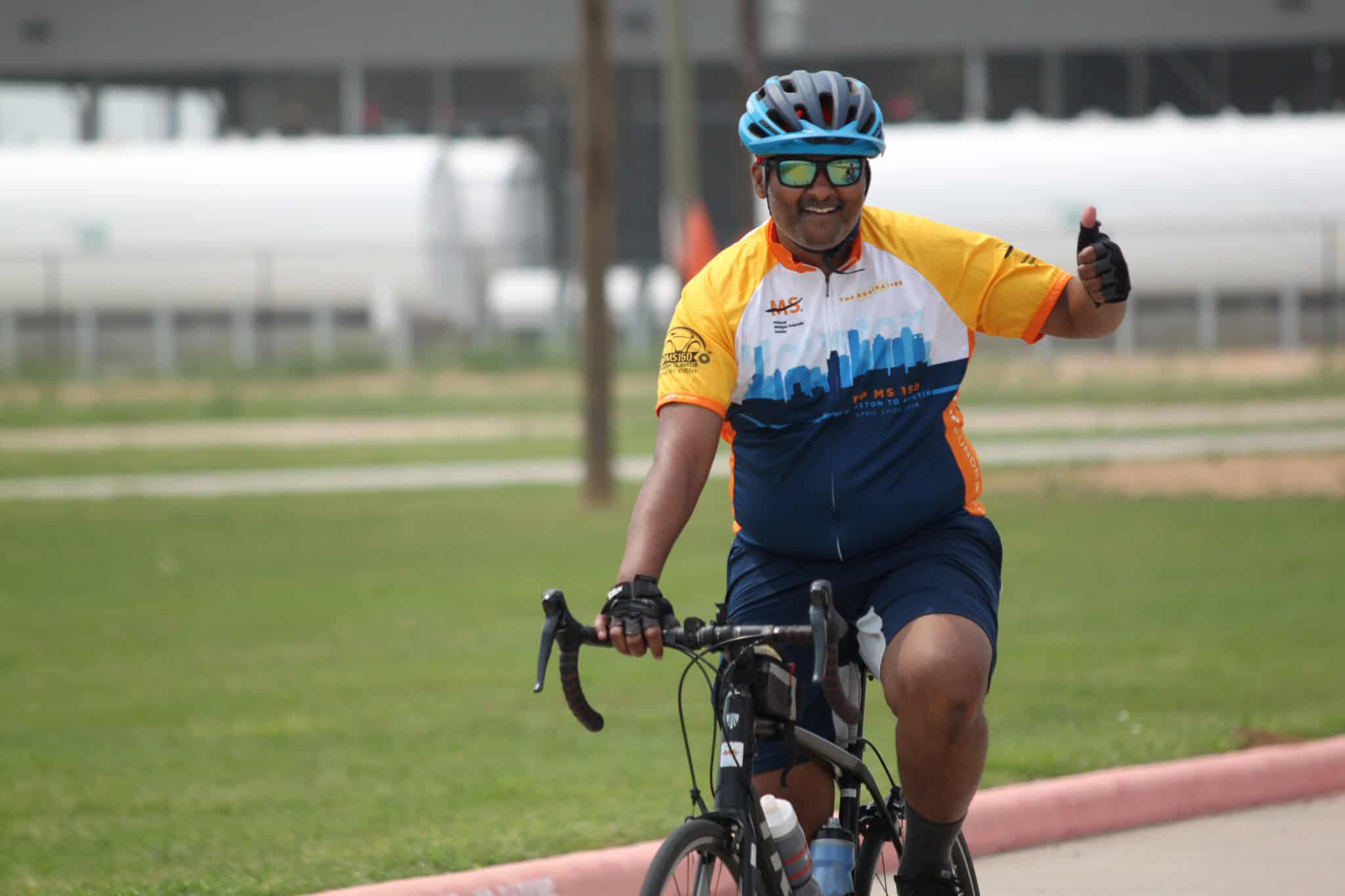 Vibrant cyclist smiling and giving thumbs-up during Bluebonnet Express bike ride event.