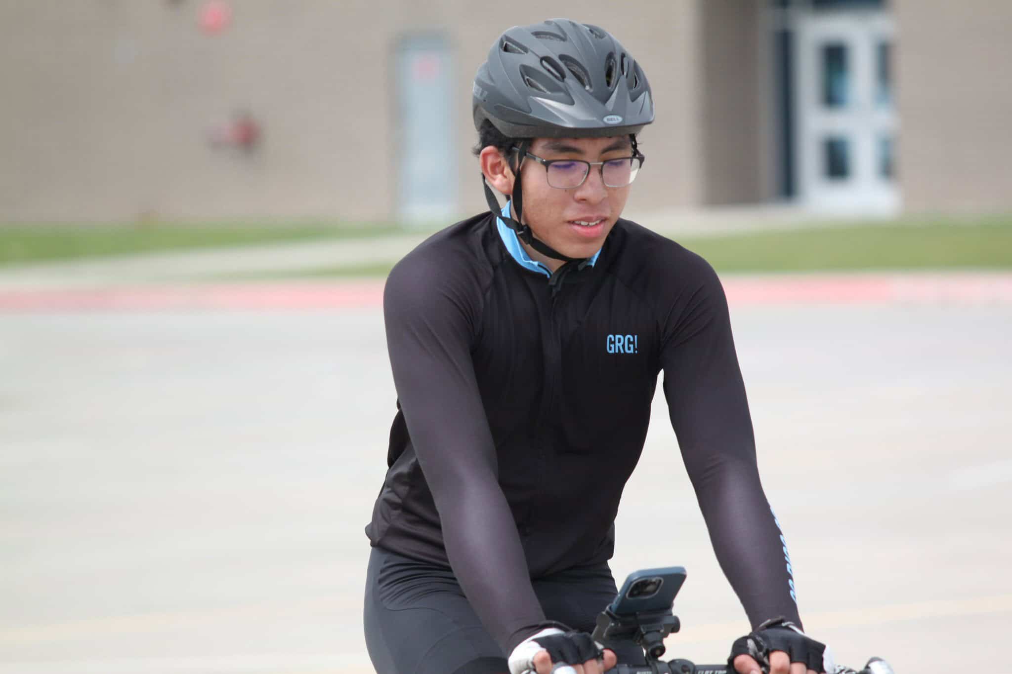 Young cyclist wearing a helmet and sports gear on a city street.