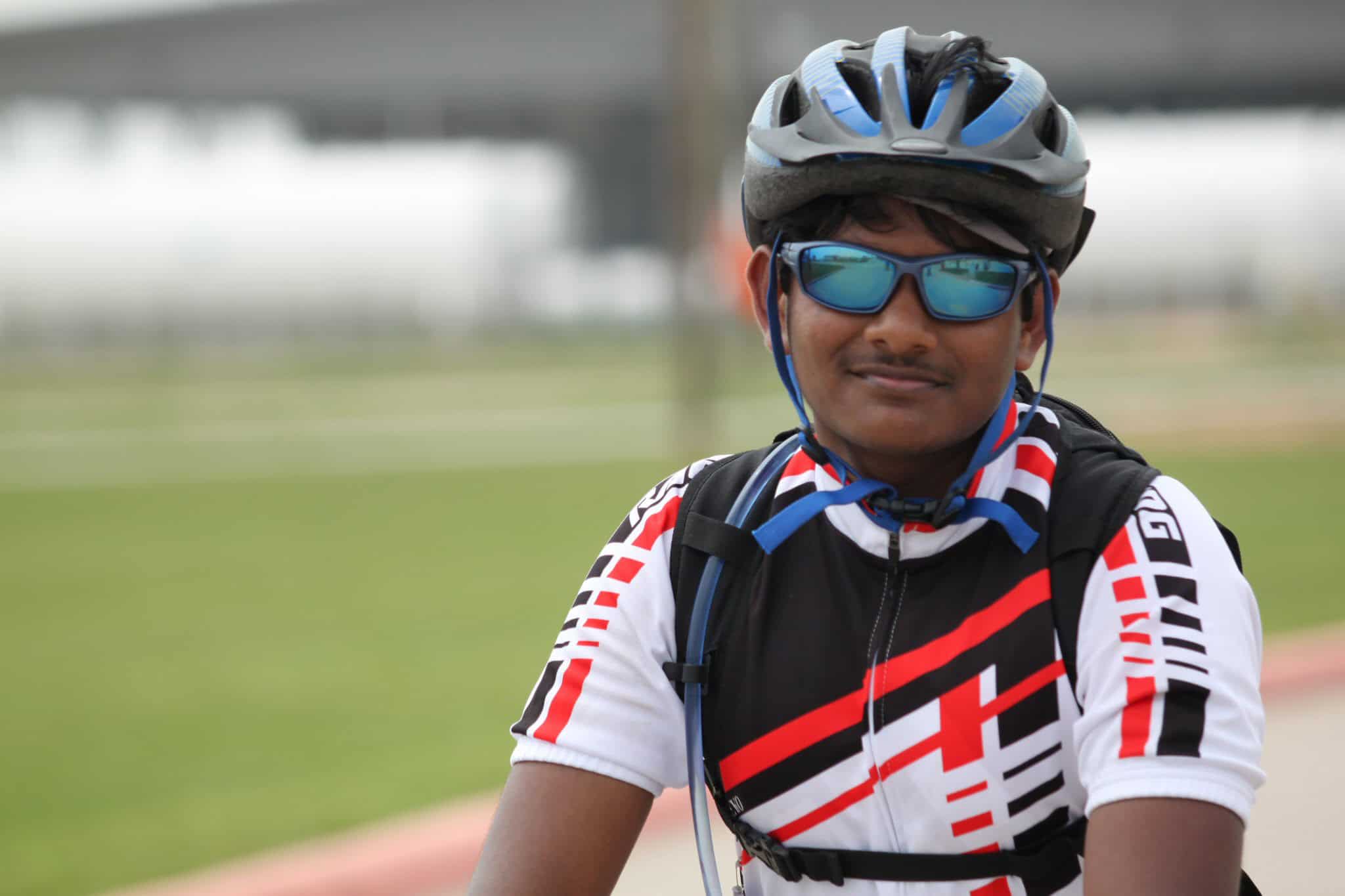 Cyclist wearing helmet and sunglasses, ready for riding, promoting Bluebonnet Express cycling services.