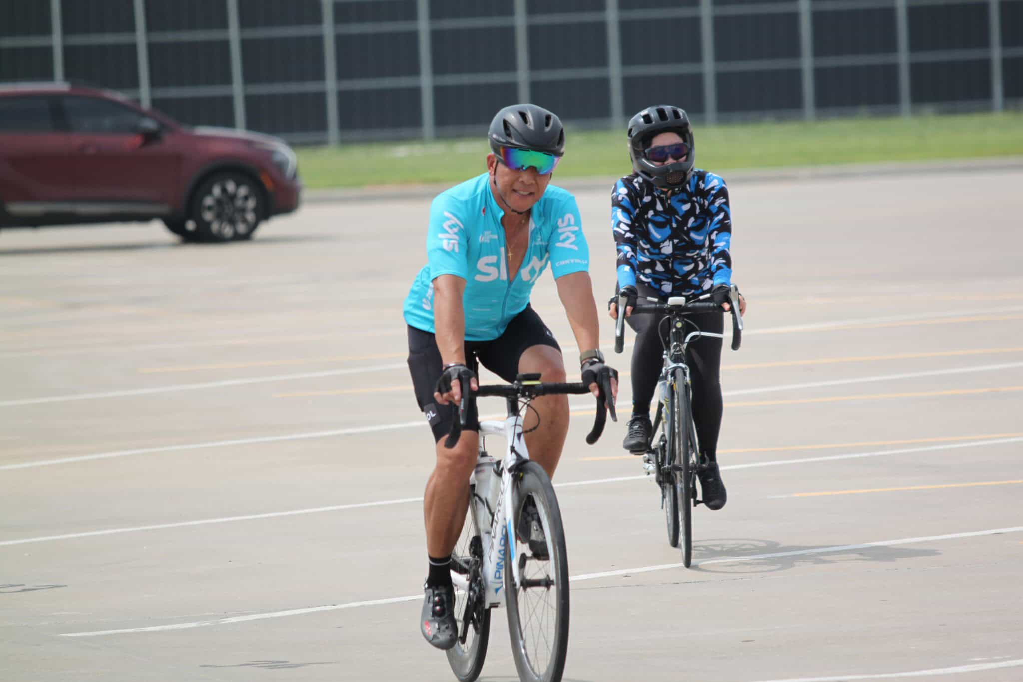 Cyclists riding bicycles on a parking lot, promoting Bluebonnet Express bike services.