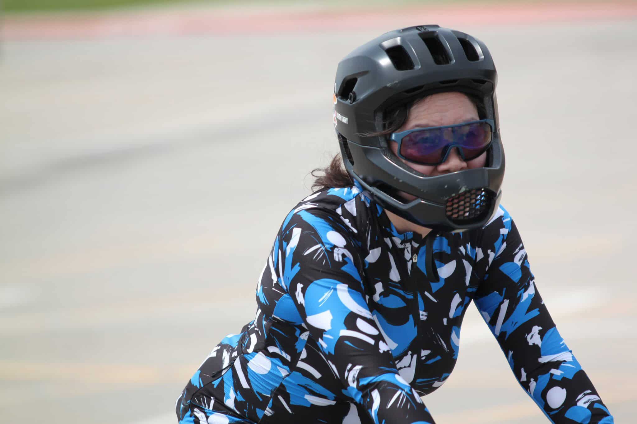 Wearing a black helmet and blue-tinted goggles, cyclist in stylish blue and black sportswear.