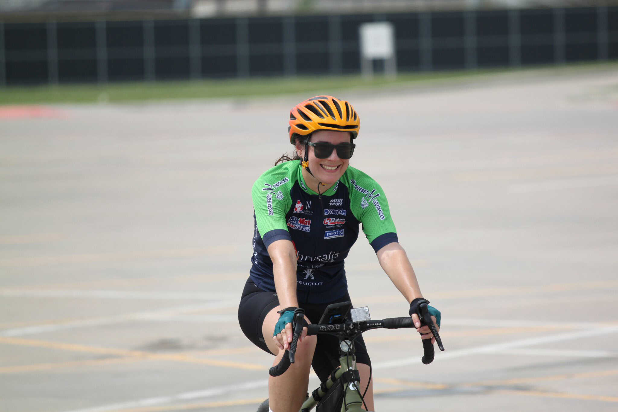 Bright female cyclist wearing helmet and sunglasses on bike at Bluebonnet Express event.