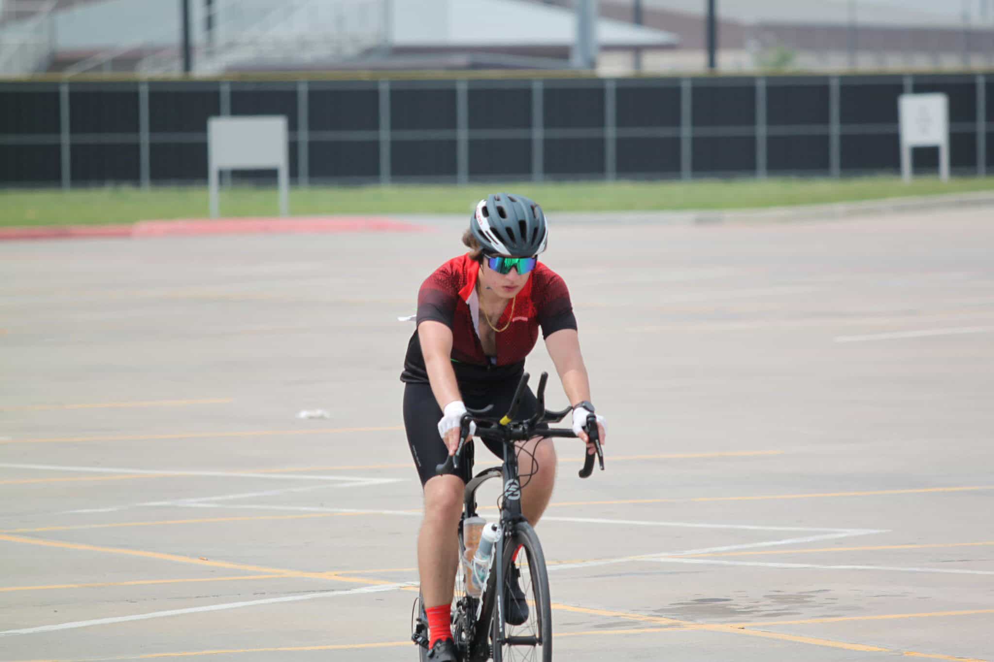 Helmeted cyclist riding on empty parking lot road for Bluebonnet Express event.