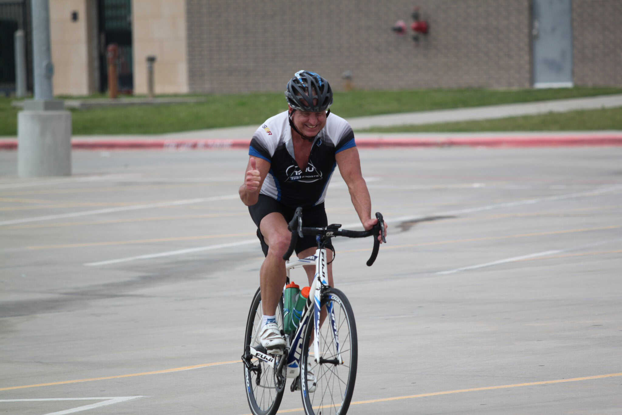 High-speed cyclist wearing helmet on urban road, Bluebonnet Express biking event.