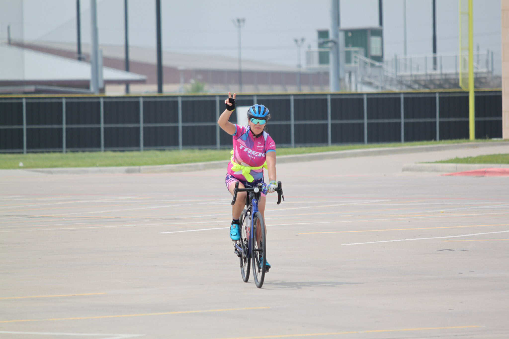 Optimized Alt Text: Female cyclist in pink jersey riding bike on empty parking lot.