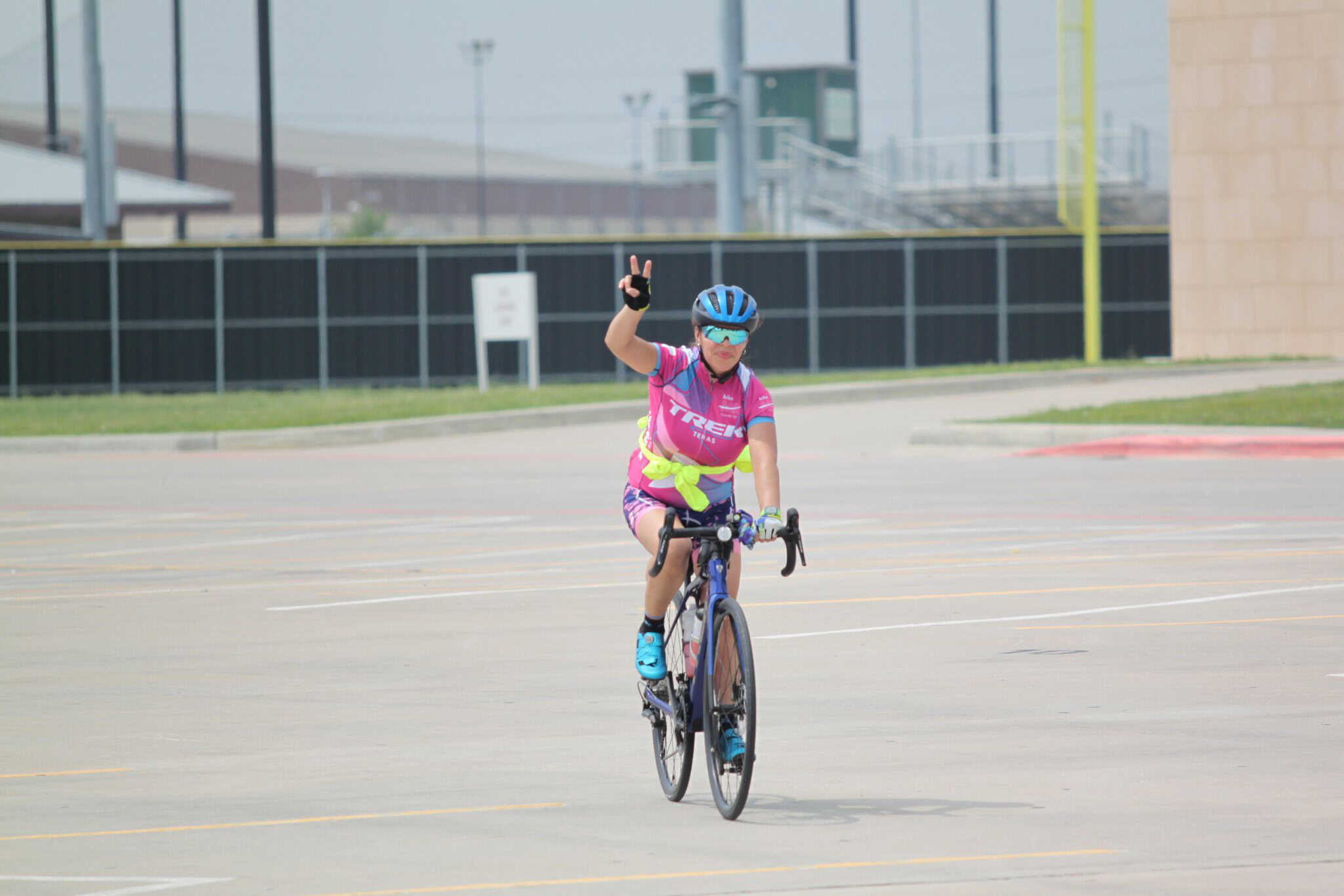 Vibrant woman cyclist wearing pink cycling jersey on bike in empty parking lot.