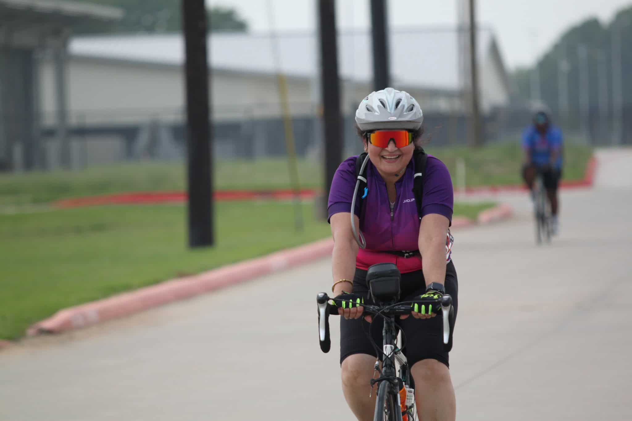 Happy woman cycling on a scenic route with Bluebonnet Express branding, embracing outdoor adventure.