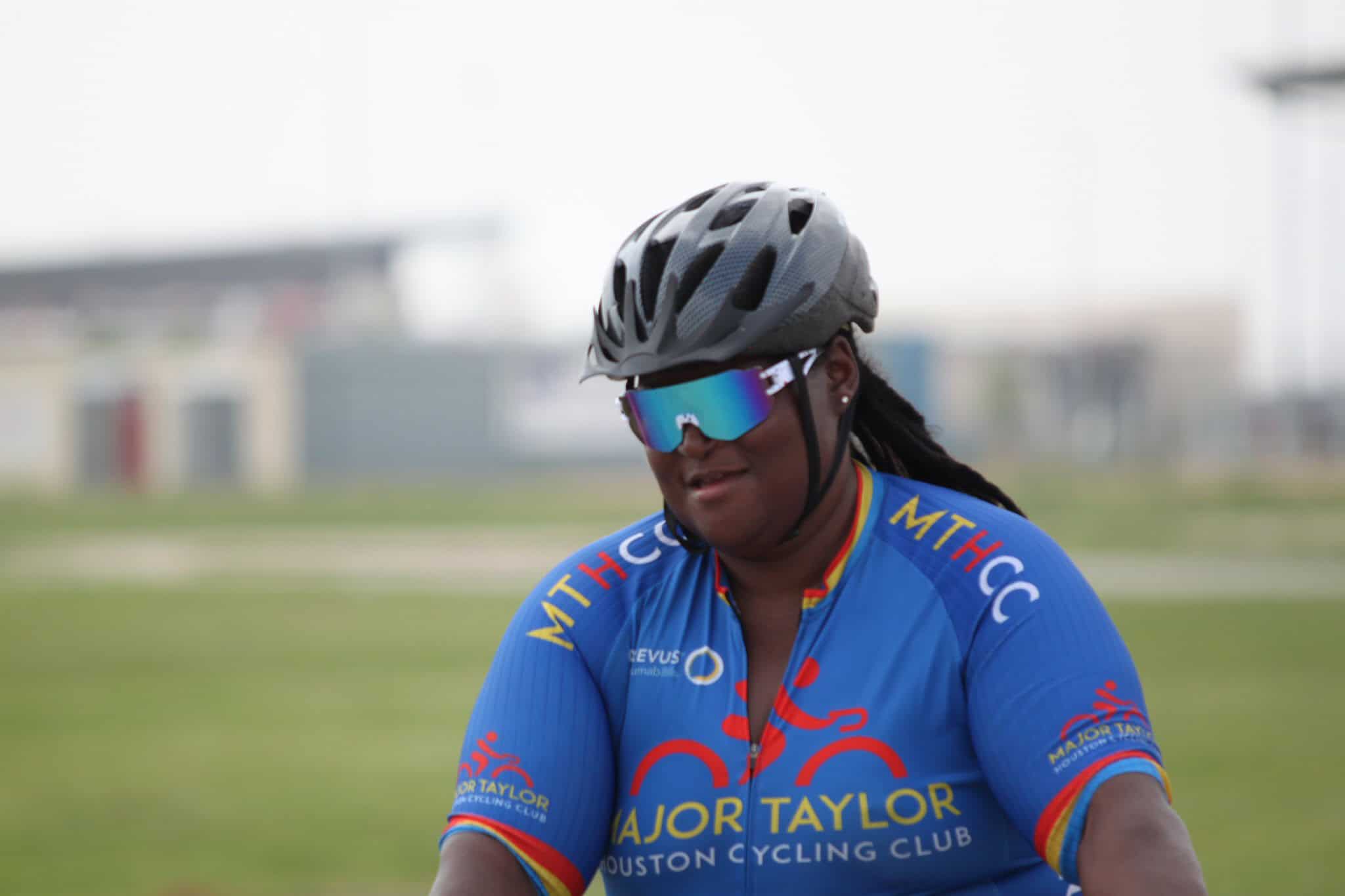 Cycling woman wearing a helmet and sunglasses, representing Bluebonnet Express team.