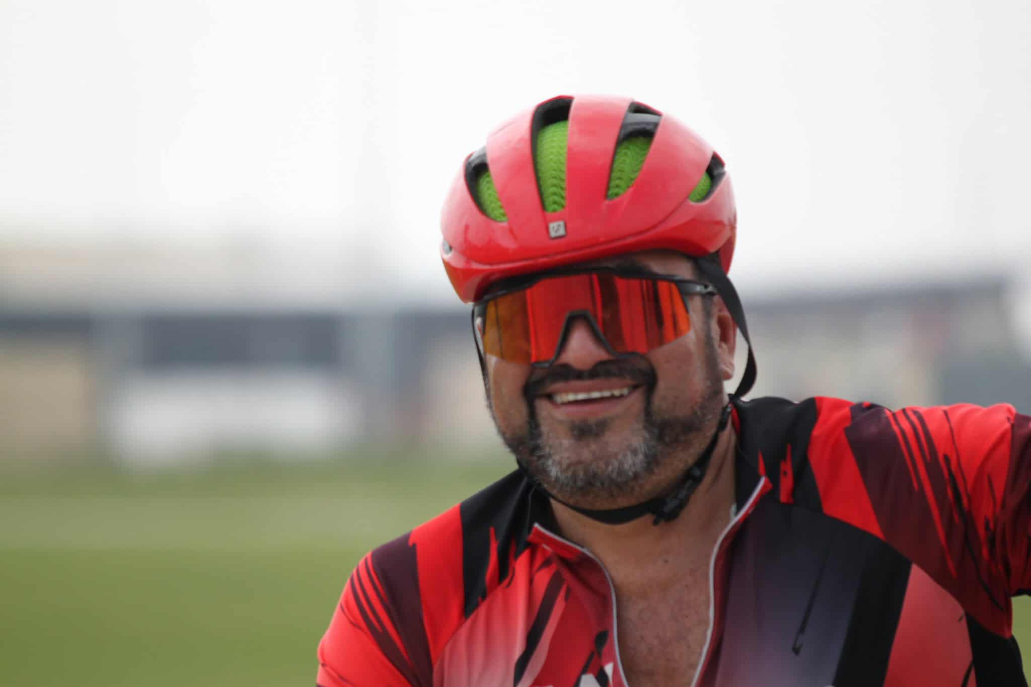 Smiling cyclist wearing red helmet and sunglasses, enjoying the Bluebonnet Express bike ride.