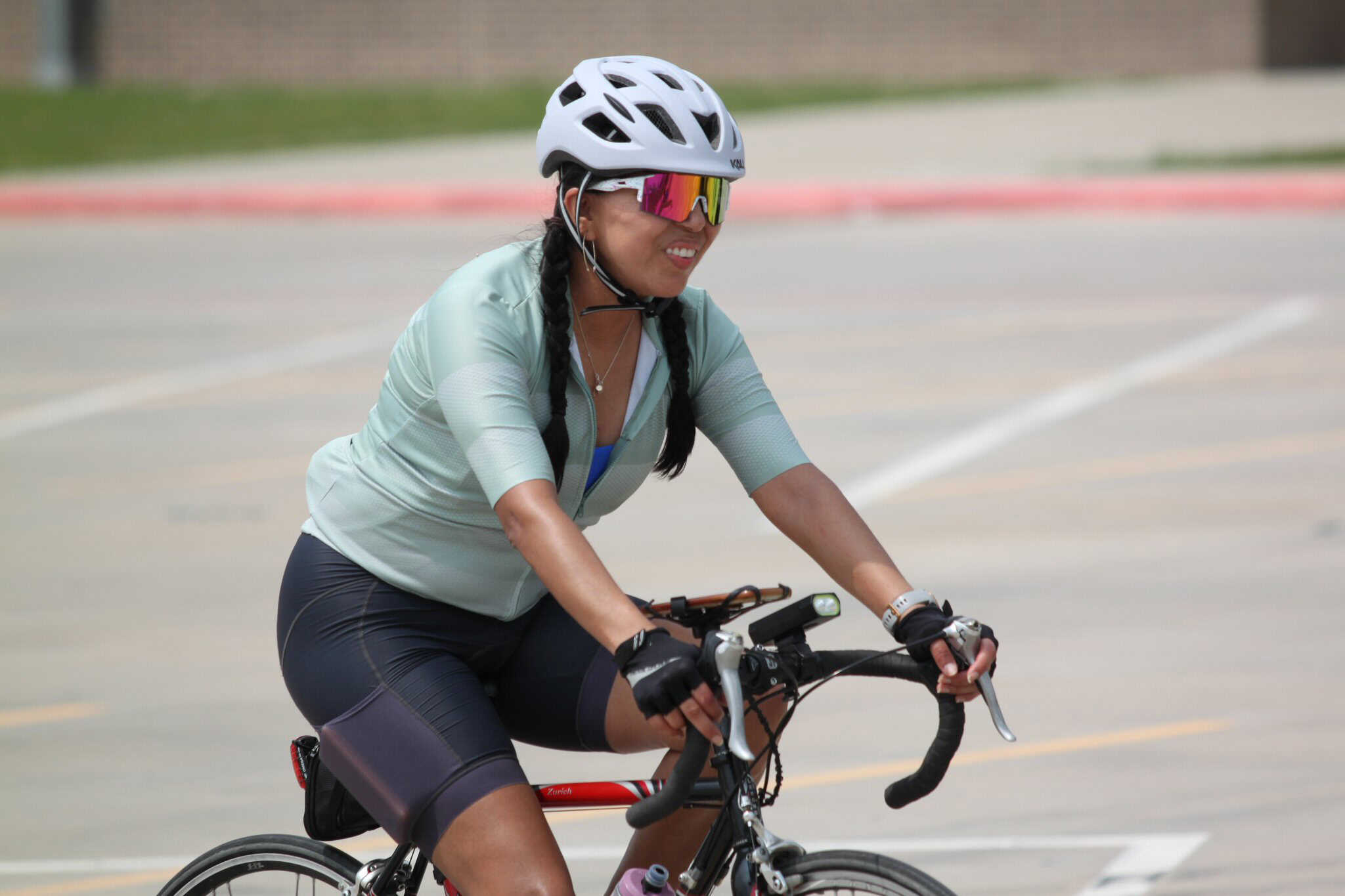 Bright woman cyclist wearing a helmet and sunglasses enjoying riding bike outdoors.