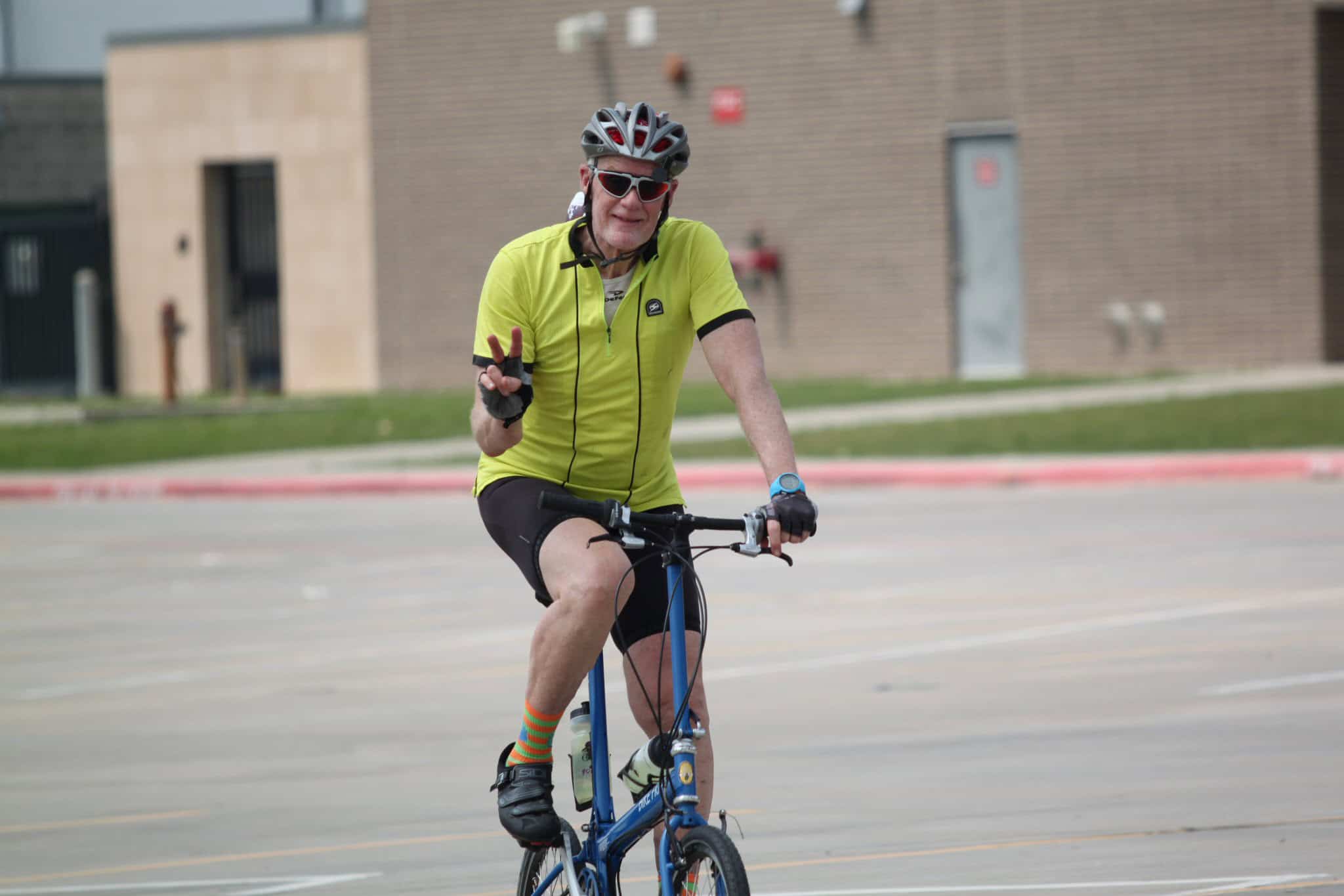 Bright yellow cycling jersey, cheerful cyclist enjoying Bluebonnet Express bike ride, wearing helmet and sunglasses.