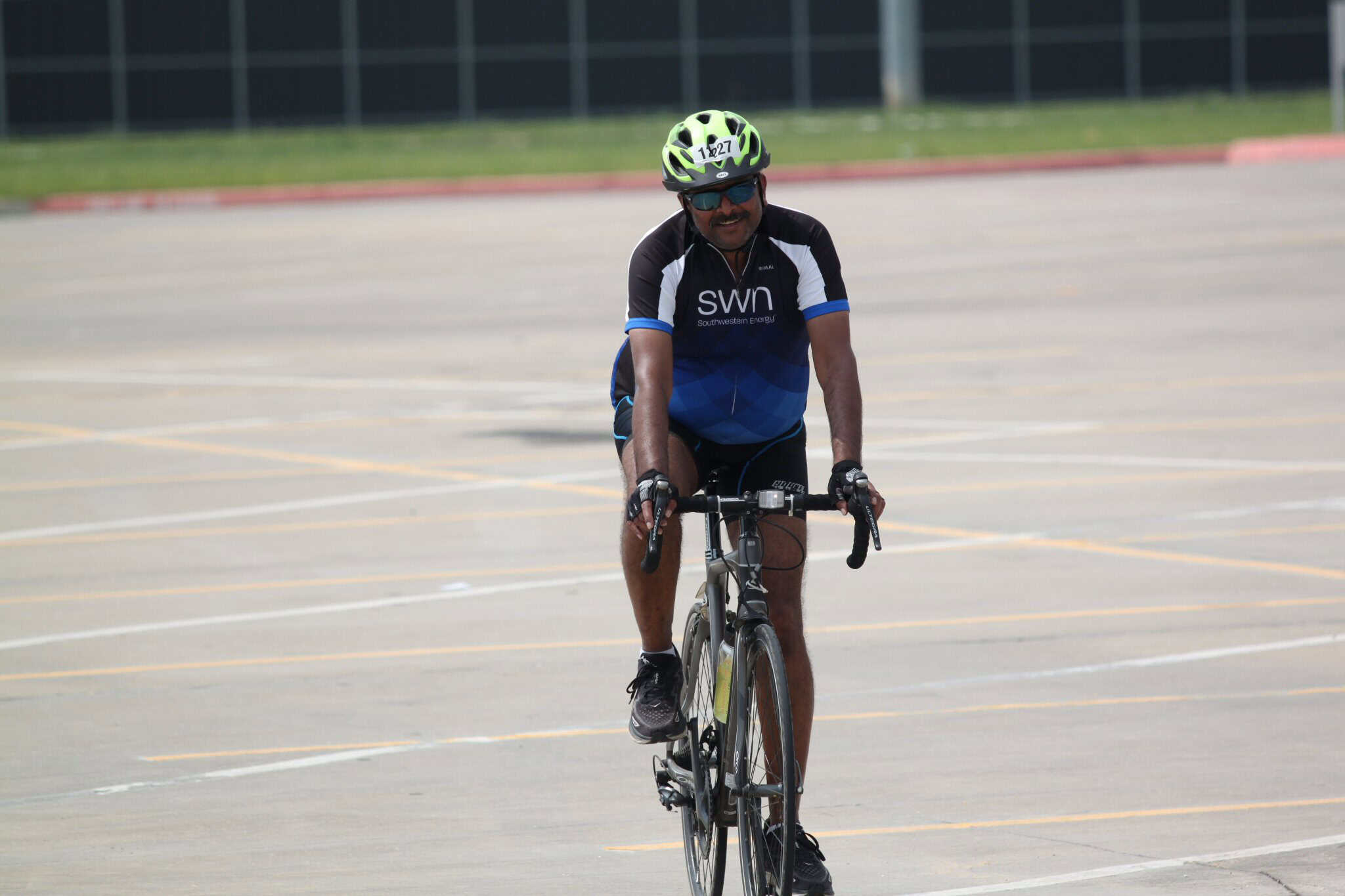 Man cycling on empty parking lot with Bluebonnet Express cycling jersey and helmet.