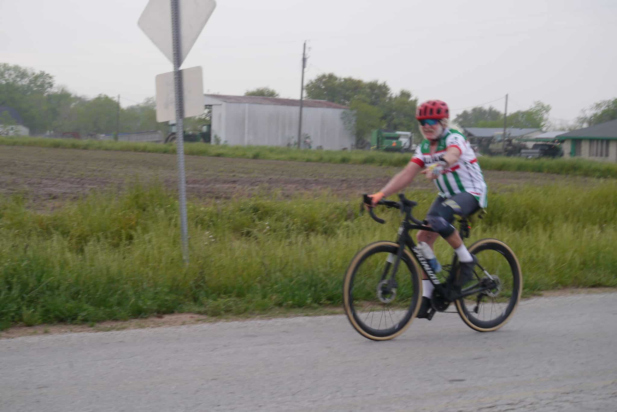 Bright cyclist riding Bluebonnet Express bike in rural area during daytime.