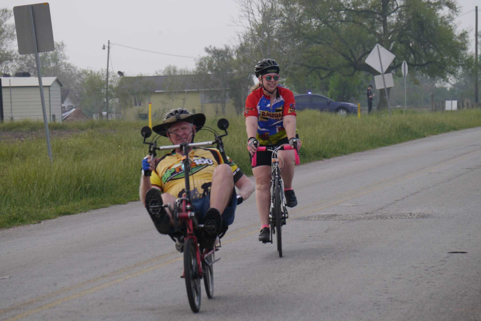 Brightly dressed cyclists enjoying a scenic bike ride on a rural road with the Bluebonnet Express branding.