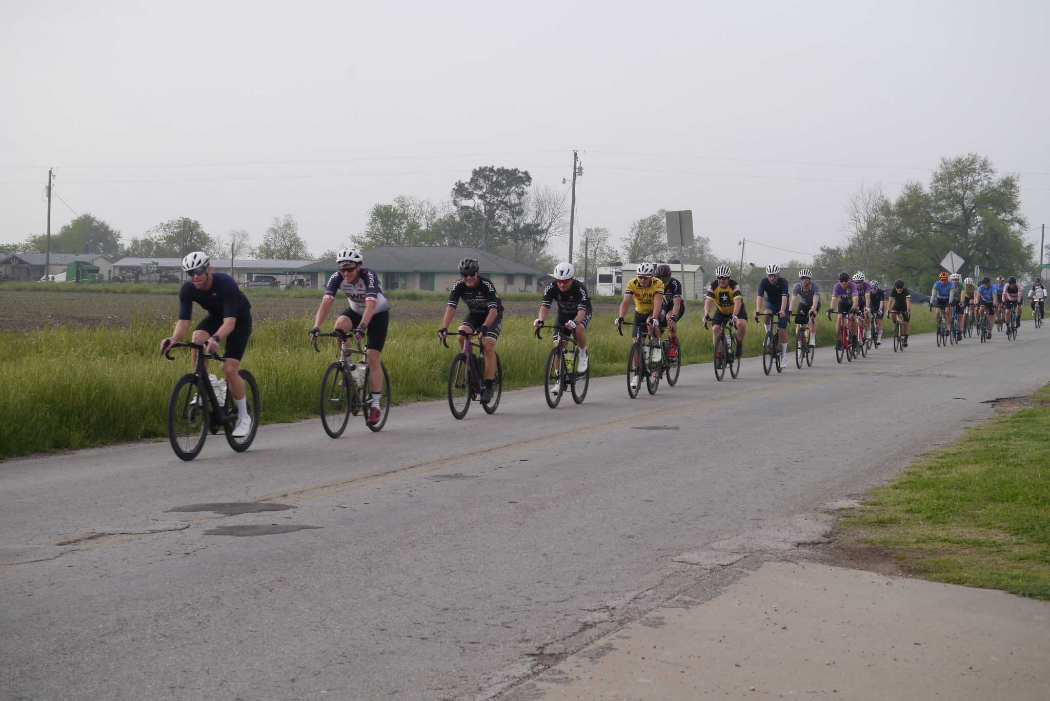 Cyclists participating in Bluebonnet Express bike event, riding on a rural road in Texas.