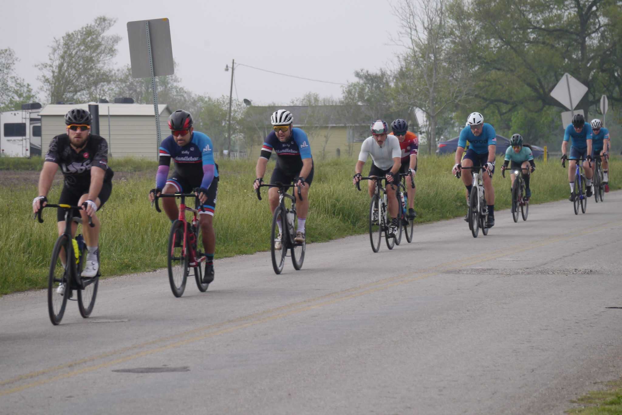 Group of cyclists riding on a rural road during daytime, promoting Bluebonnet Express biking event.