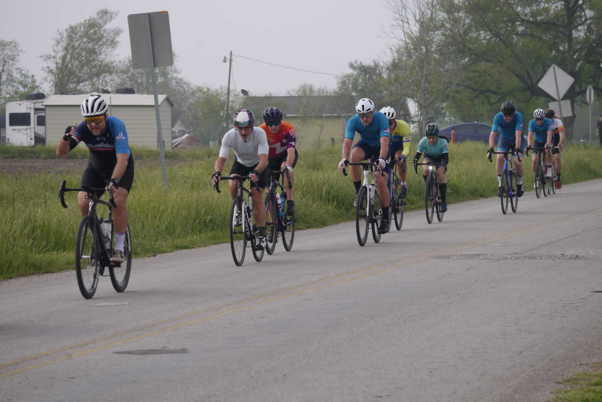 Vibrant group of cyclists riding on a scenic road during the Bluebonnet Express bike race event.