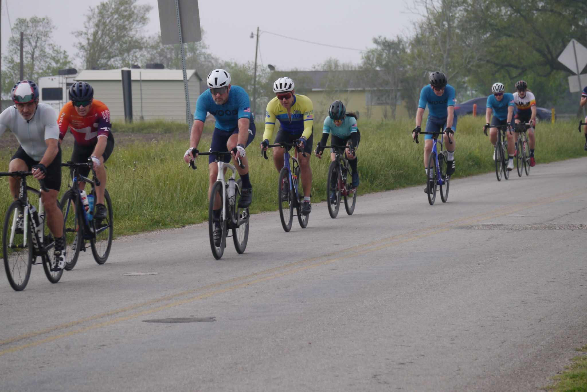 Cycling team participating in Bluebonnet Express race on rural road with green landscape.