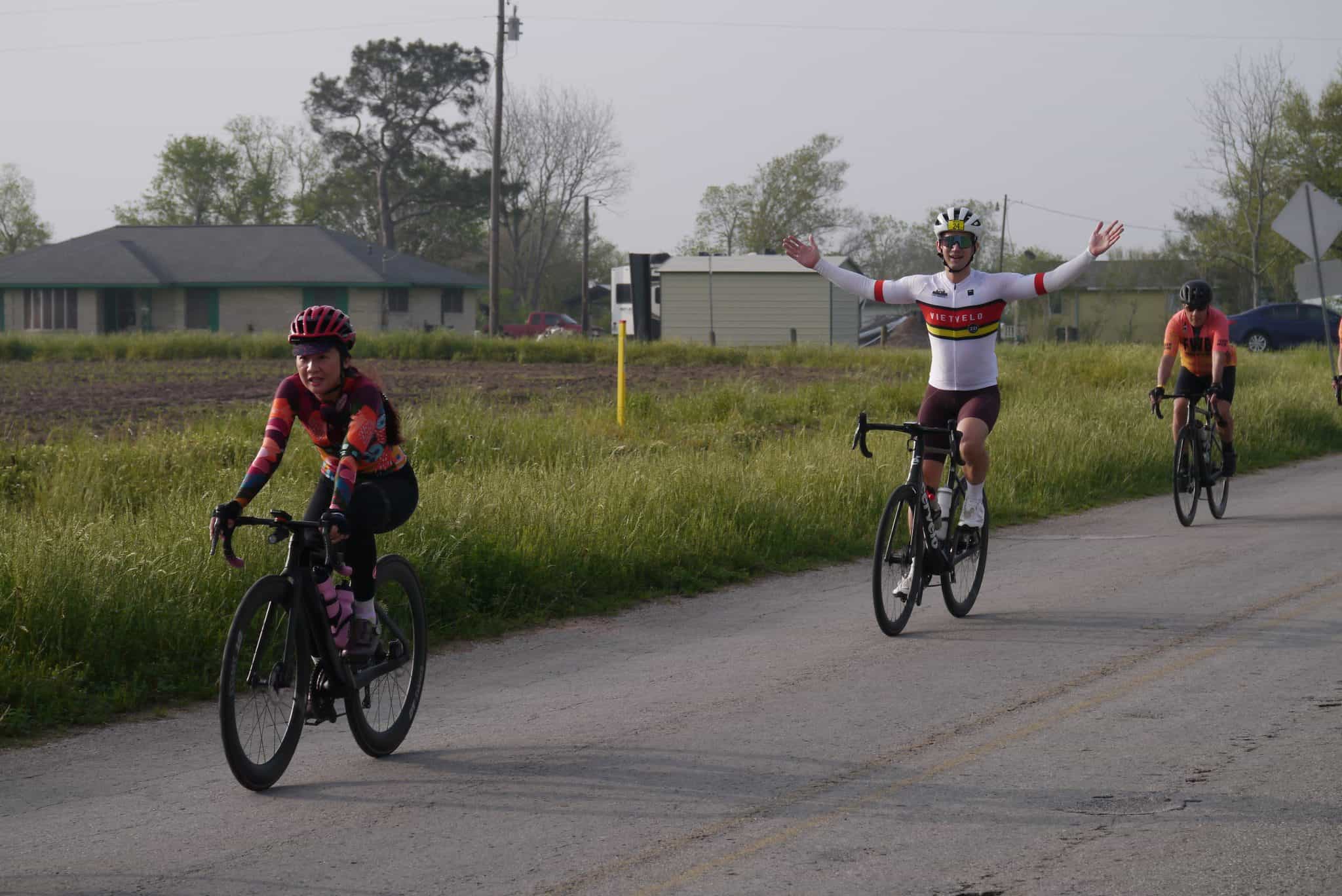 Brightly colored cyclists riding on a rural road during a cycling event in Texas.