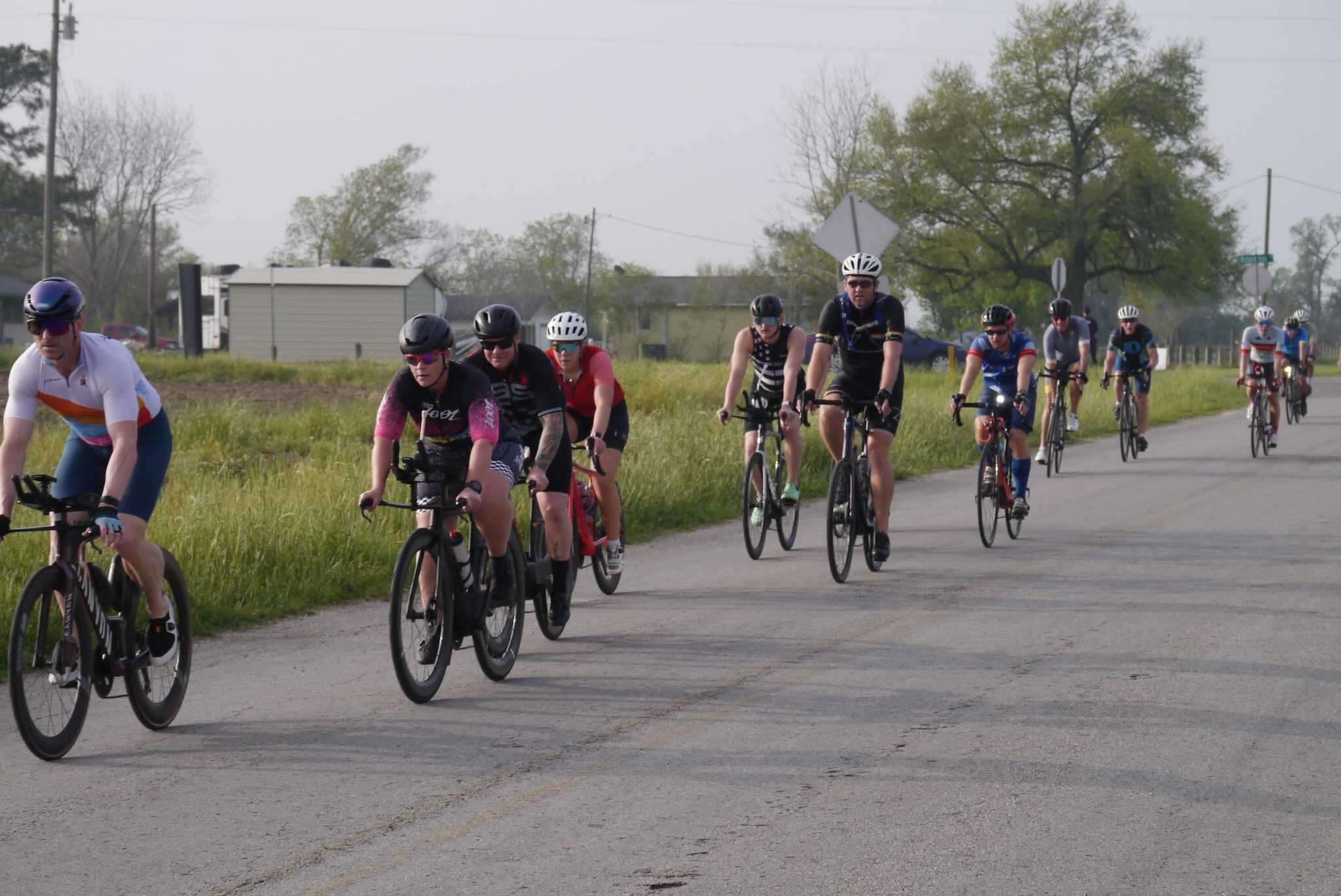 Vibrant group of cyclists riding on a rural road during daytime for Bluebonnet Express event.