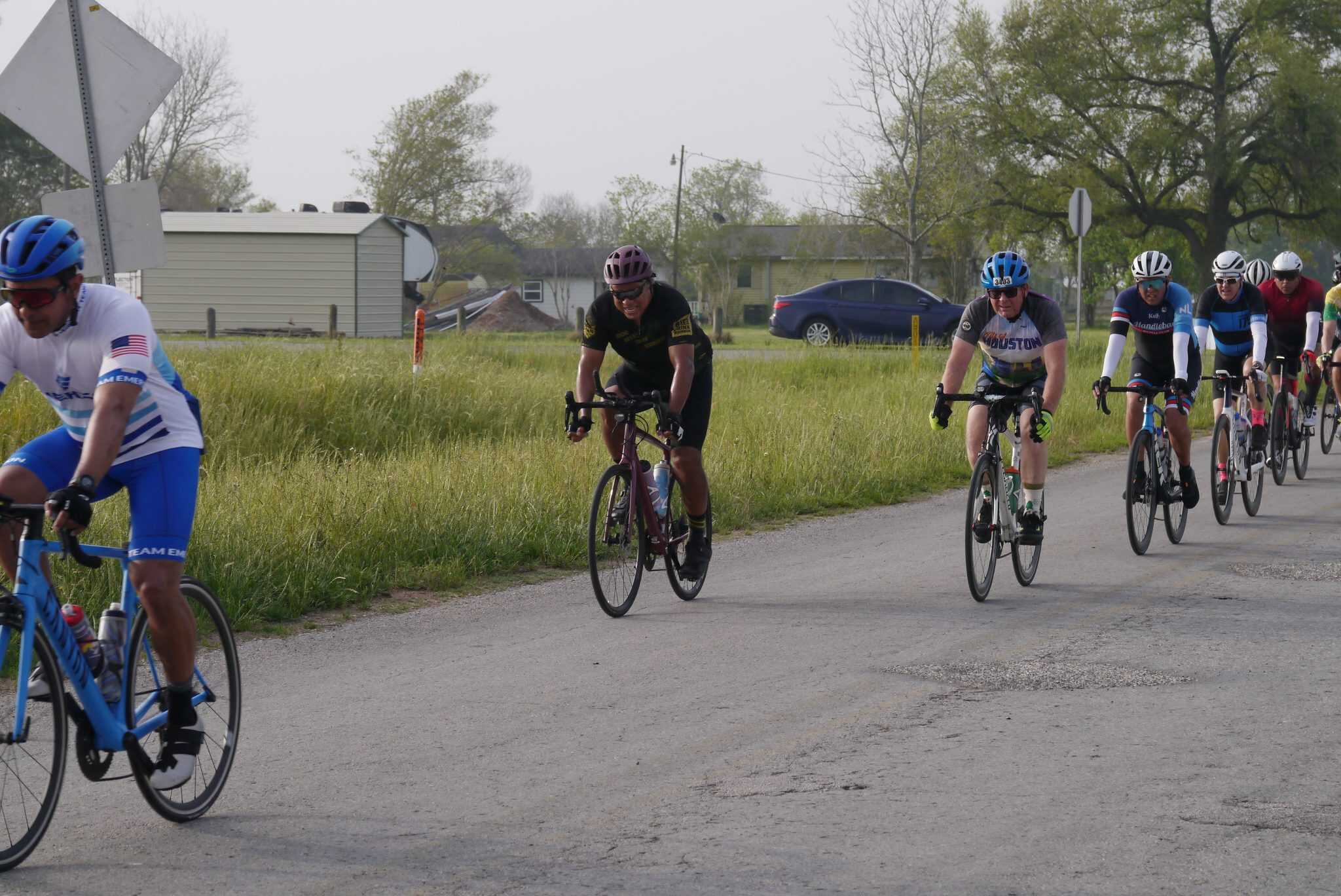 Riders participating in the Bluebonnet Express cycling event on a rural road, emphasizing eco-friendly transportation.