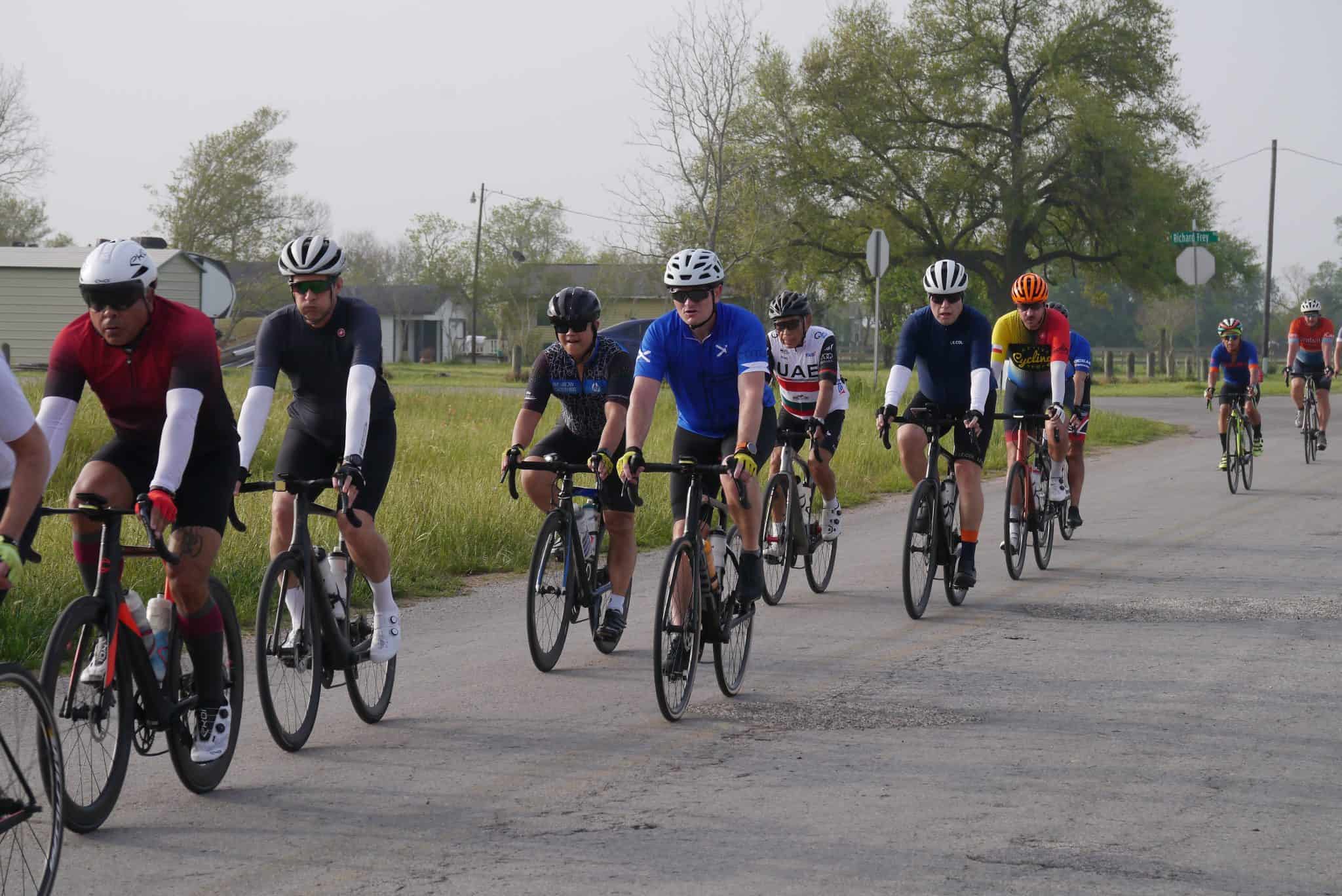 Highway cycling group on a scenic rural road for Bluebonnet Express event, promoting outdoor fitness and community.