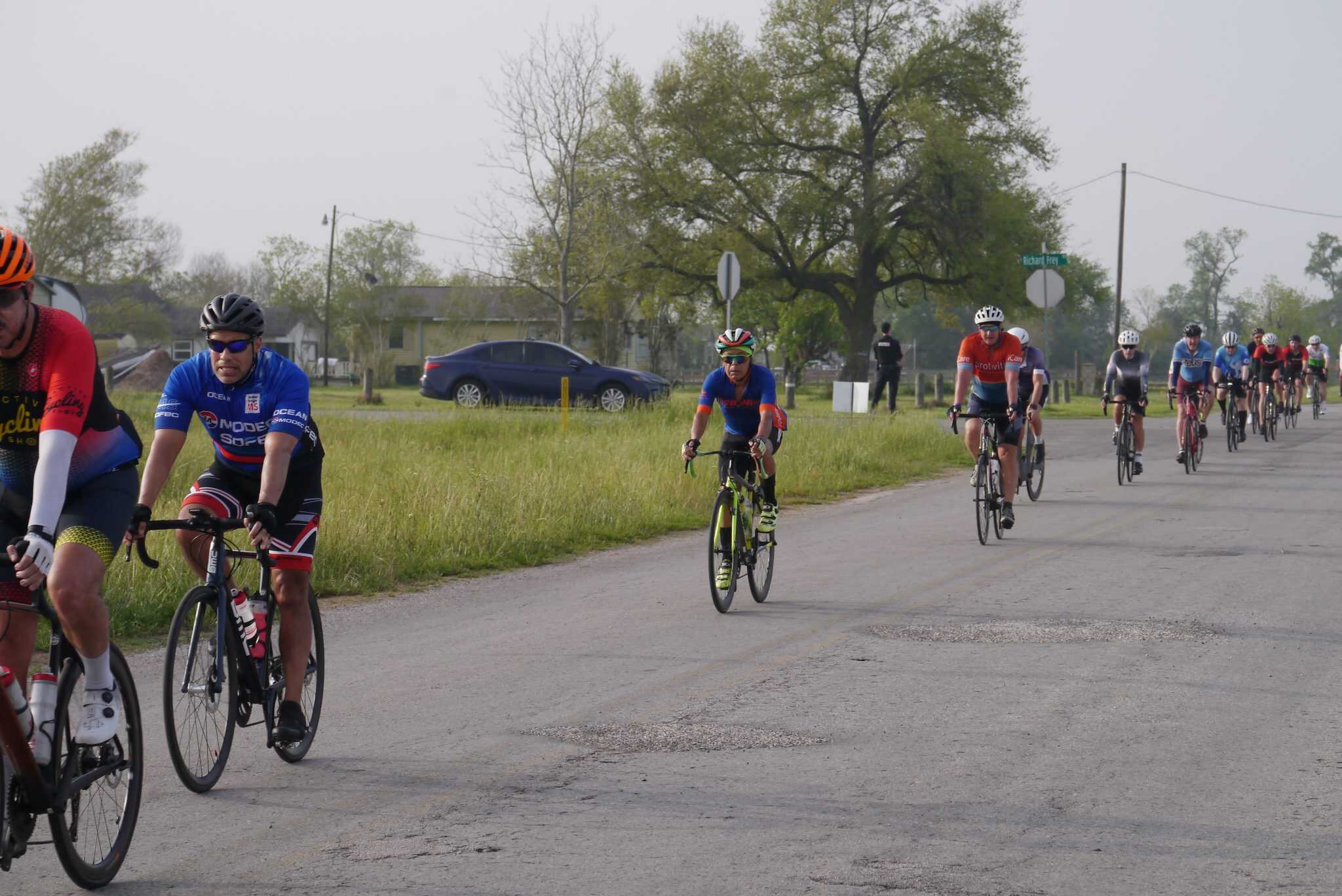 Vibrant cyclists participating in the Bluebonnet Express bike race on a rural road.