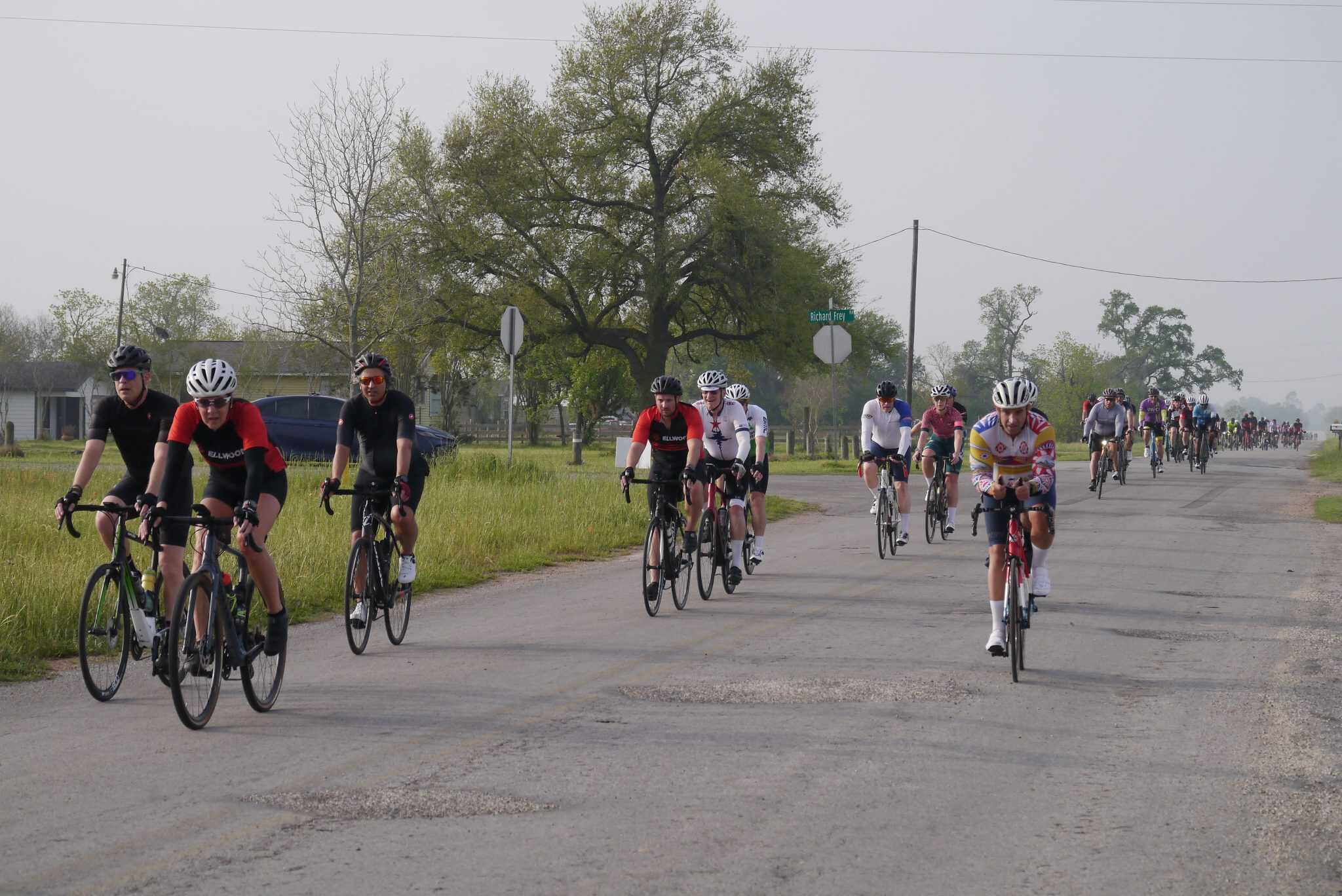 Cycling group riding through rural area on bikes, outdoor biking event, Bluebonnet Express race.