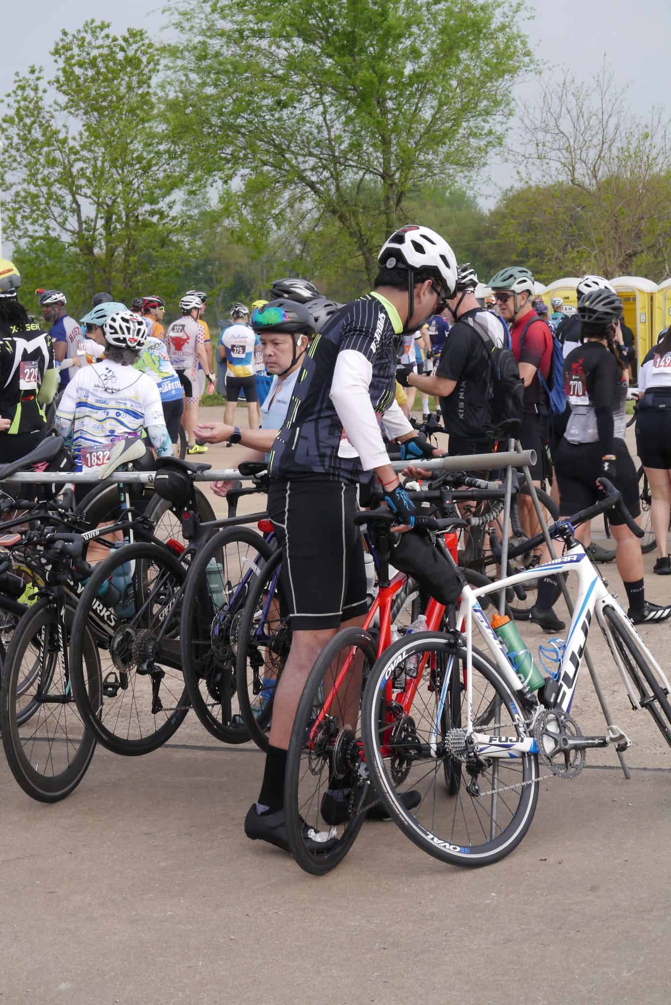Riders preparing for Bluebonnet Express cycling event, surrounded by bikes and fellow cyclists.