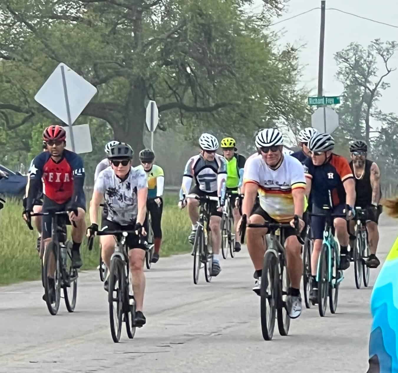 Bright group of cyclists riding together on a scenic outdoor route during daytime.