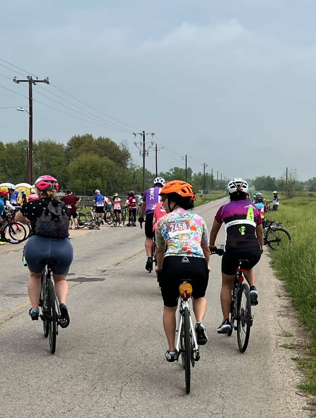 Brightly colored bikes and helmets during a group cycling event along a rural road.