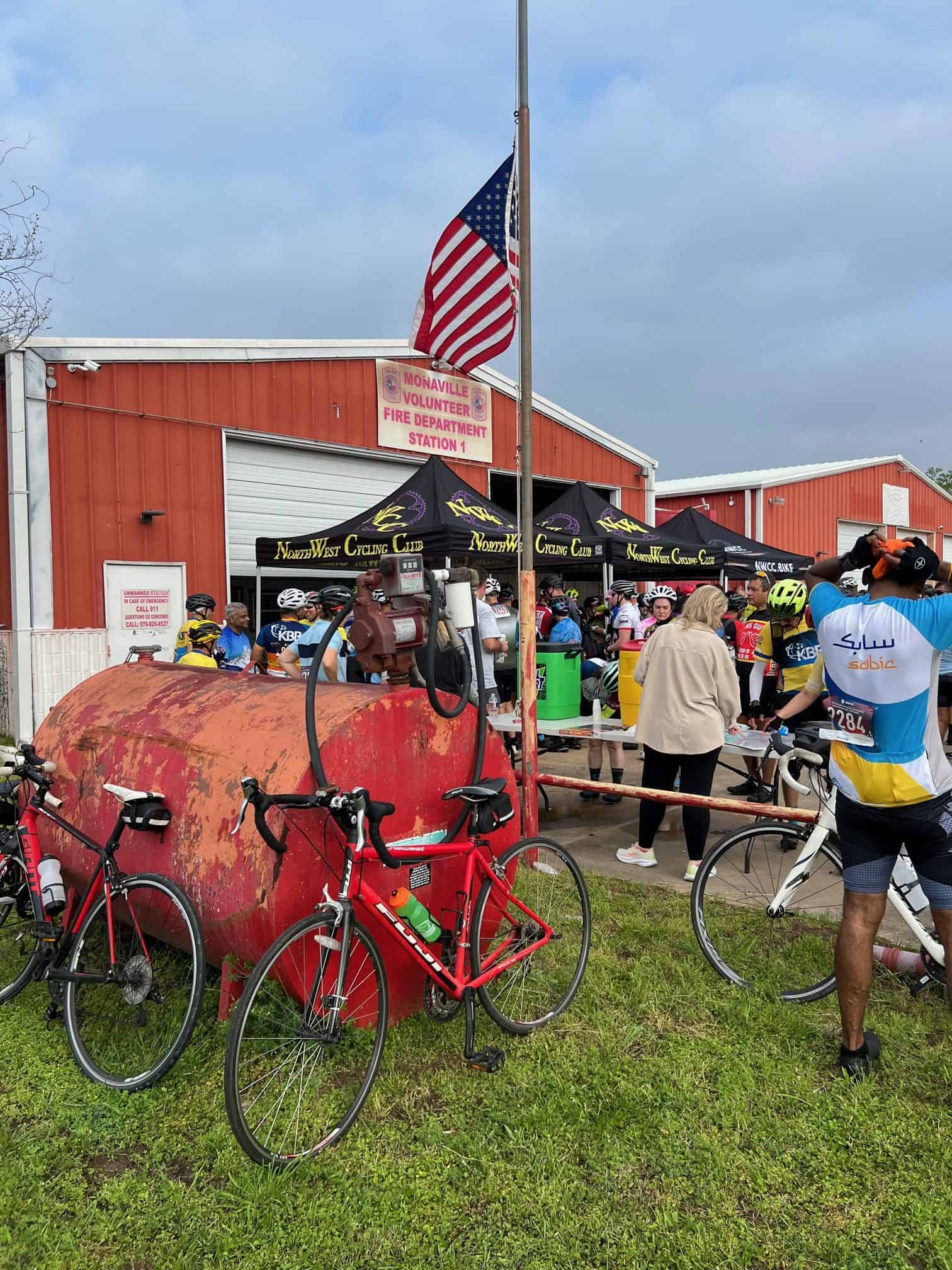 Brightly colored cycling event at Monaville Volunteer Fire Department station with cyclists gathering at Bluebonnet Express.