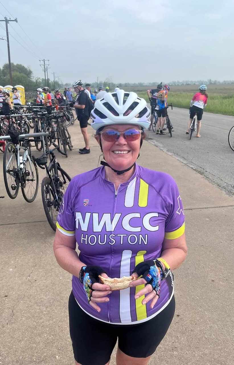 Cyclist with helmet and purple NWCC Houston jersey, smiling at Bluebonnet Express cycling event.