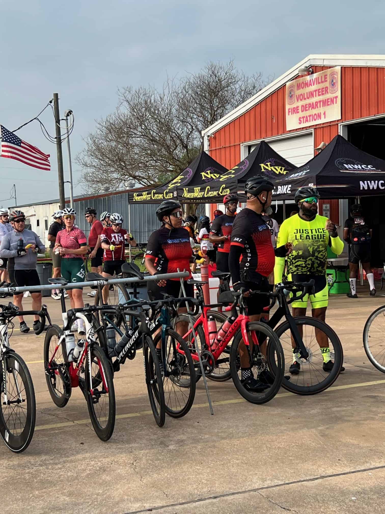 Riders gather with bikes at Bluebonnet Express cycling event in front of a fire station.
