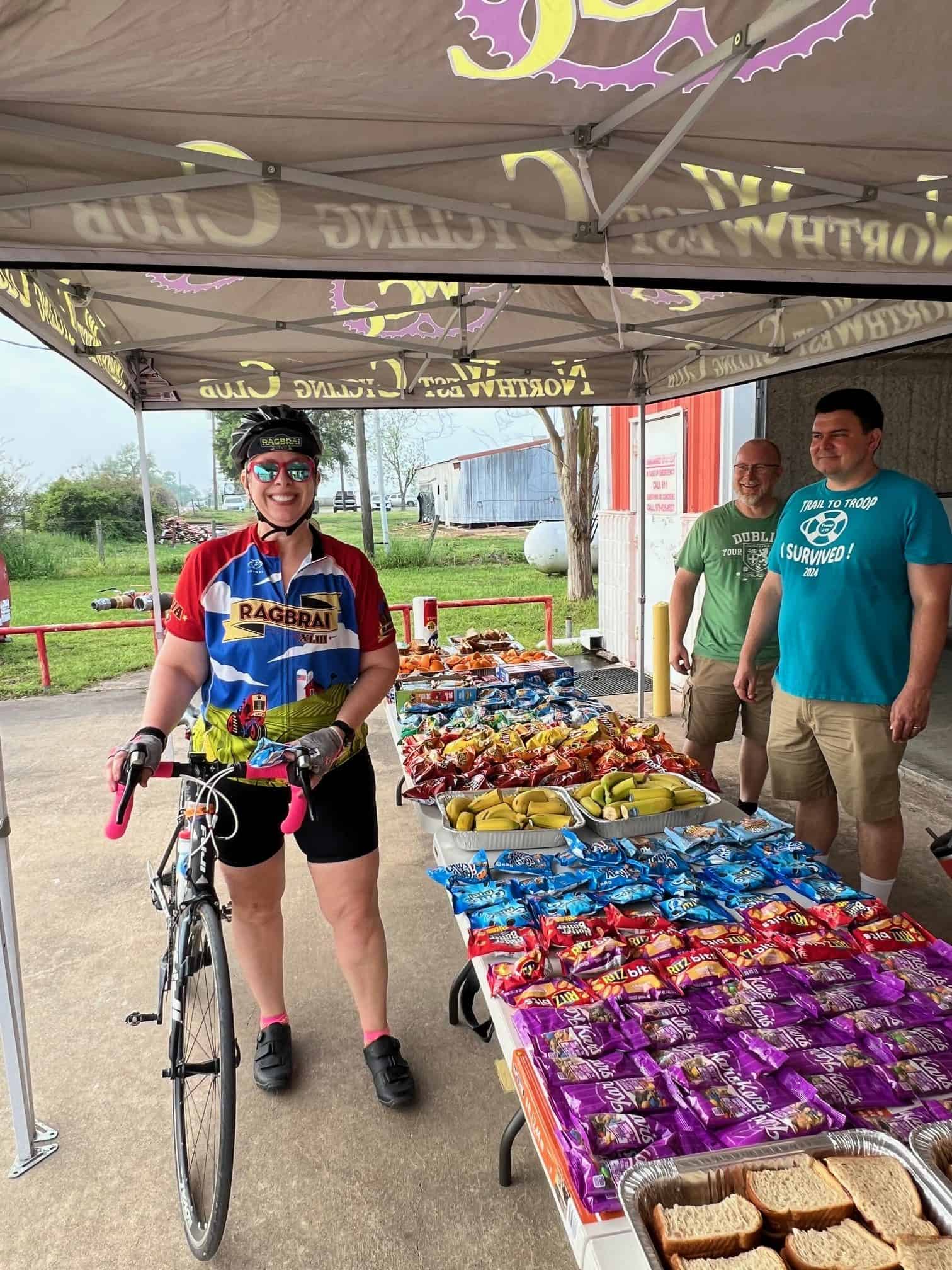 Bright cyclist at snack stop with chips, bananas, and sandwiches, supporting the Bluebonnet Express bike event.
